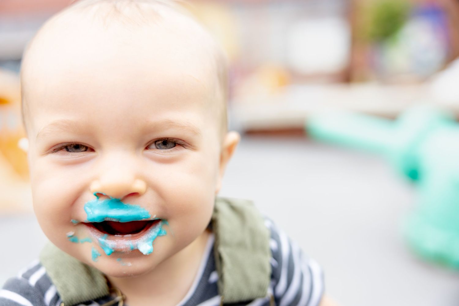 A messy and joyful moment with blue frosting covered smile during cake smash photography.
