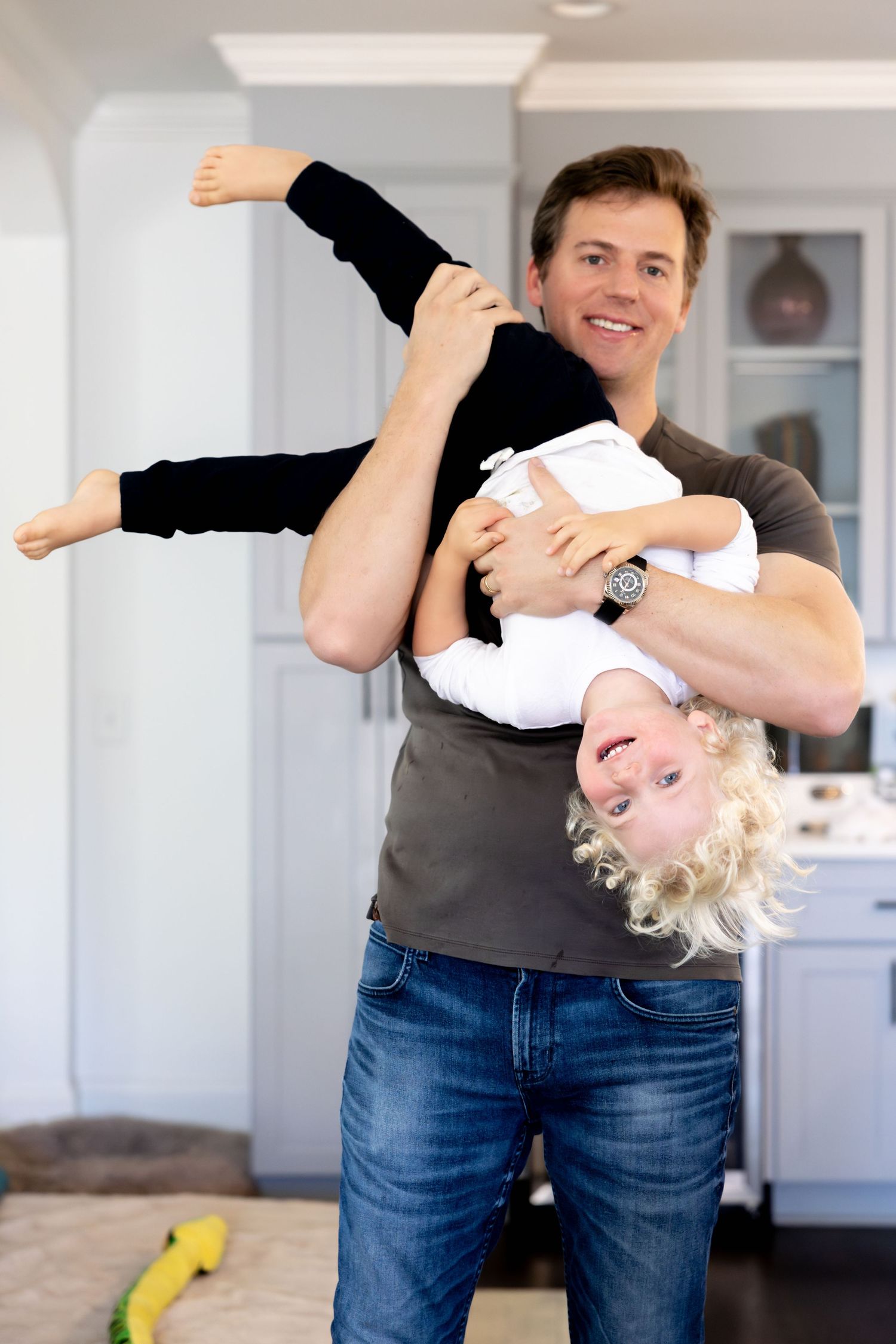 Adult playing and lifting child during a break from art activities in a bright home setting.