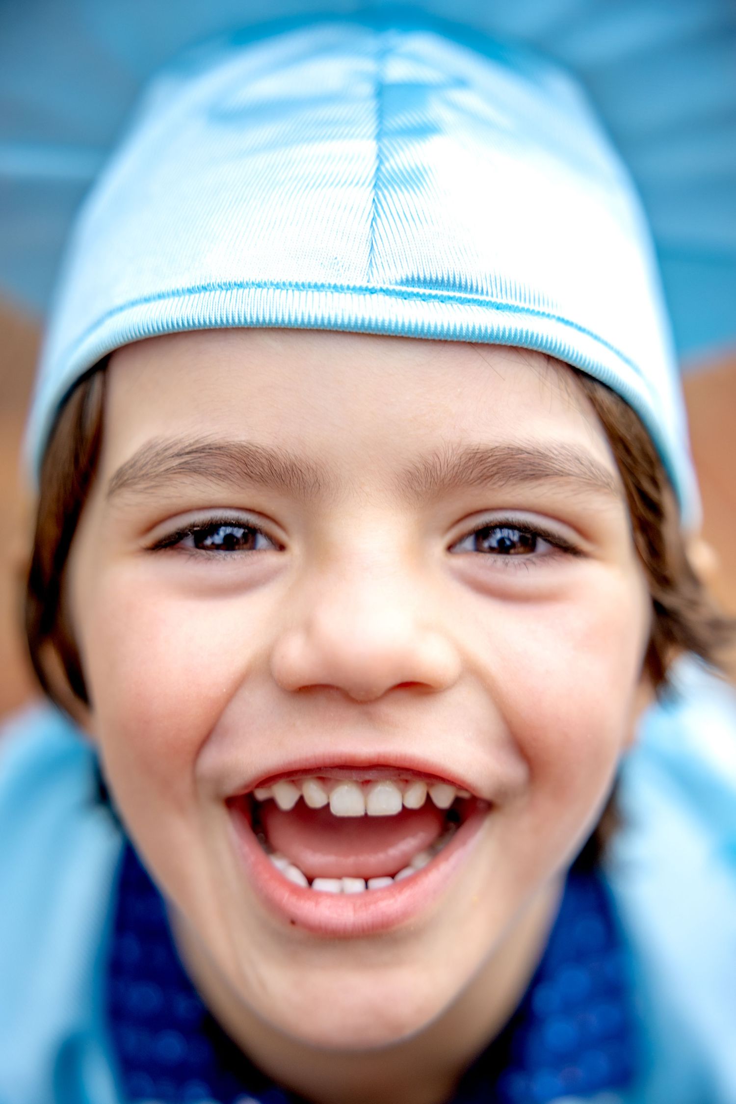 Close-up sequence showing joyful expressions in a light blue preschool graduation cap.