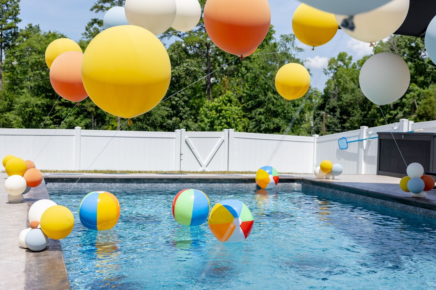 Colorful balloons floating in swimming pool during outdoor birthday party.