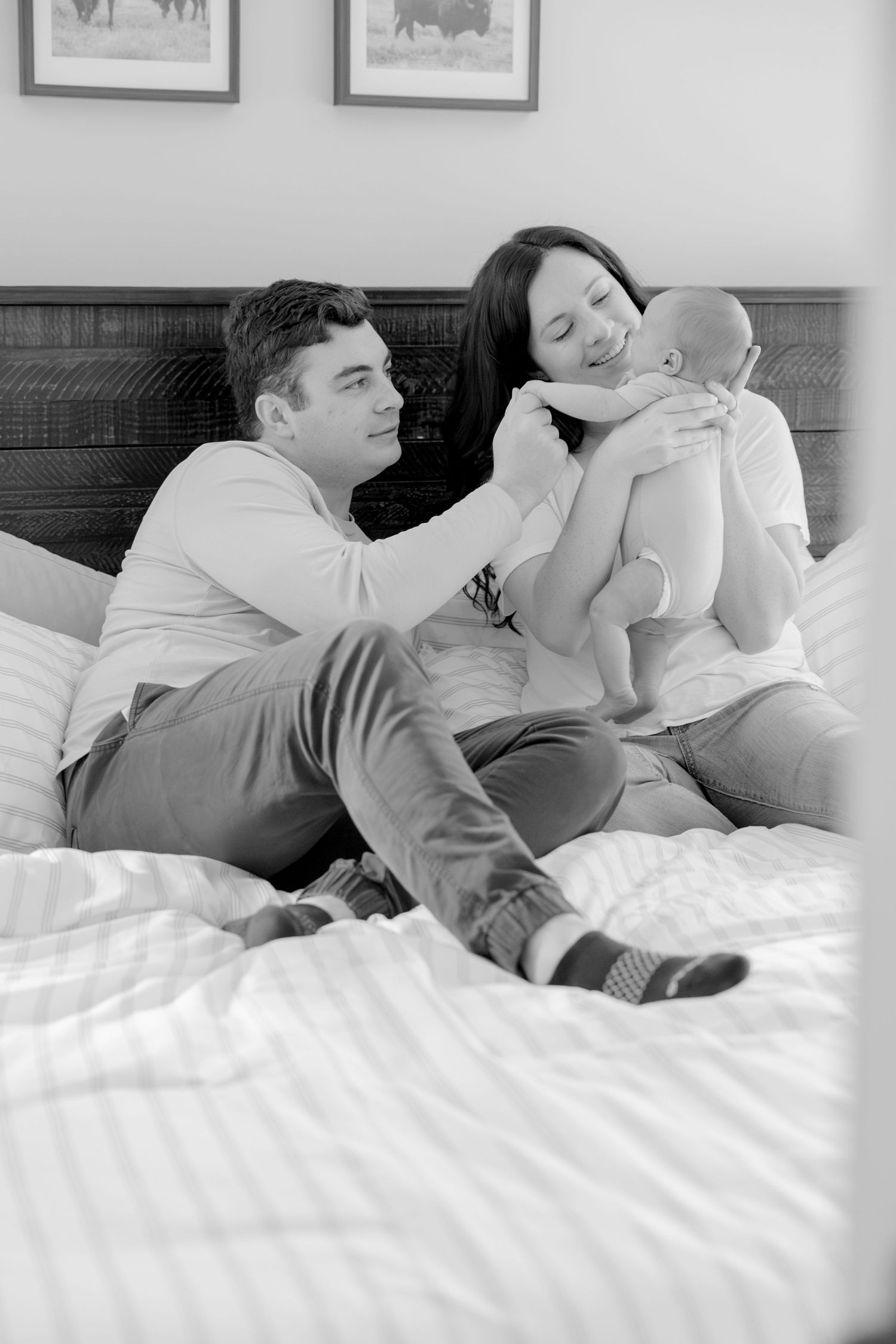 Black and white photo of family relaxing together with newborn on bed.