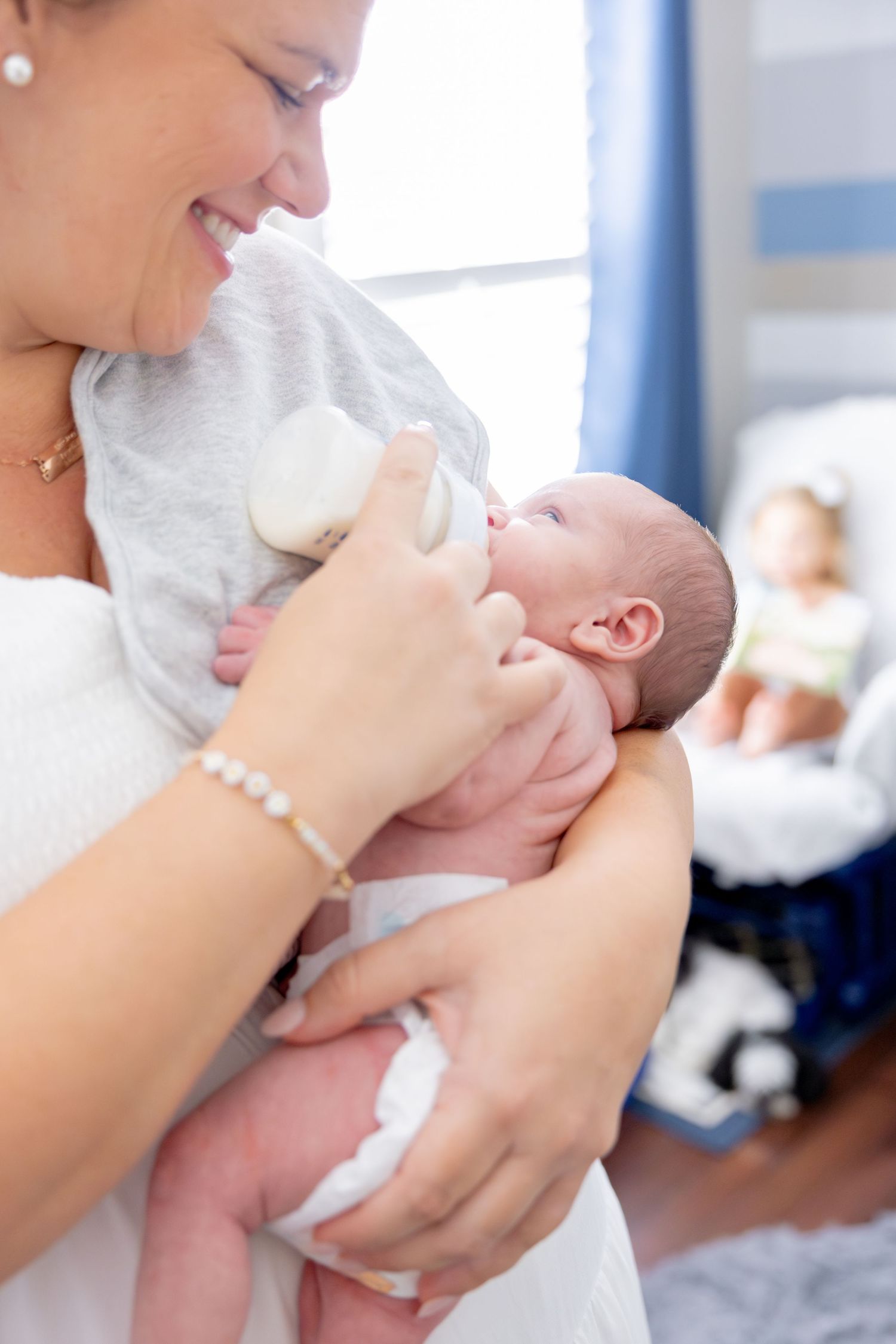 Tender moments of a baby being cradled and fed in a nursery setting.