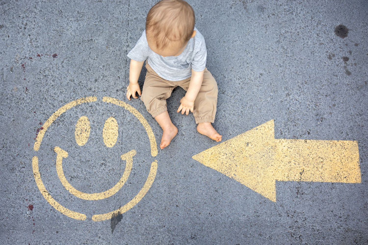 Yellow smiley face and arrow designs painted on grey concrete surface at Camp North End in Charlotte, NC.