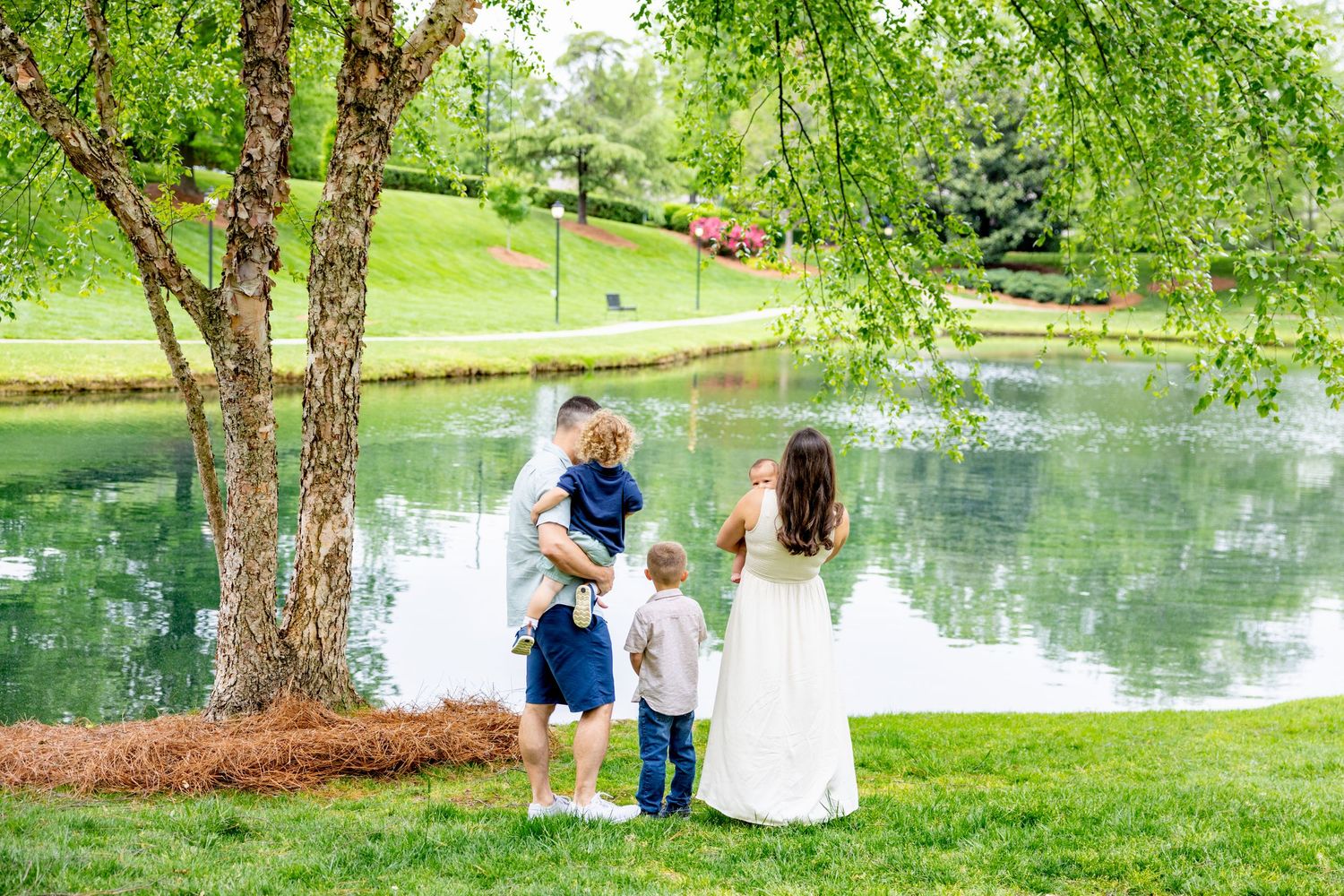 Beautiful spring day with family activities by a serene pond under weeping willow trees.