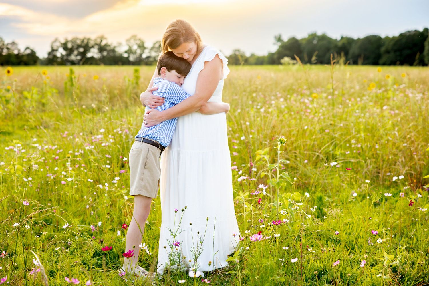 Loving moment shared in a wildflower meadow during golden hour wearing white dress and khaki shorts at Blue Hill Garden in Monroe, NC.