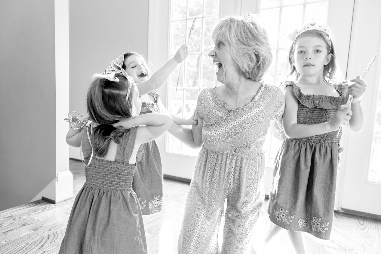 Black and white candid photo of a joyful dancing moment in a bright room.