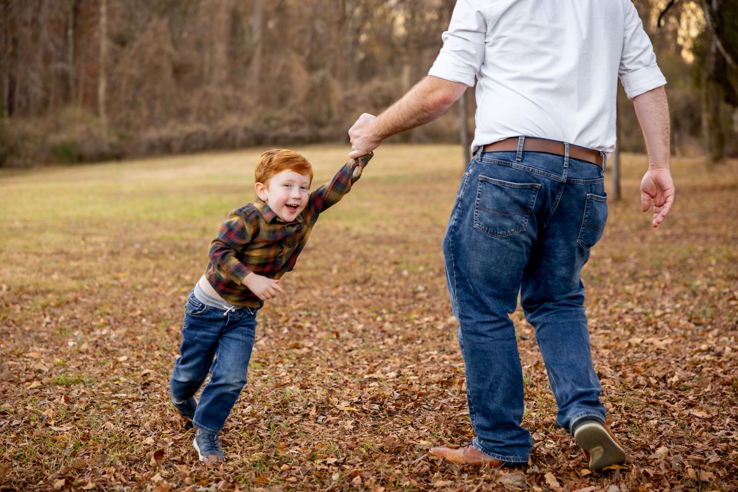 Playful interaction between adult and child on leaf-covered ground.