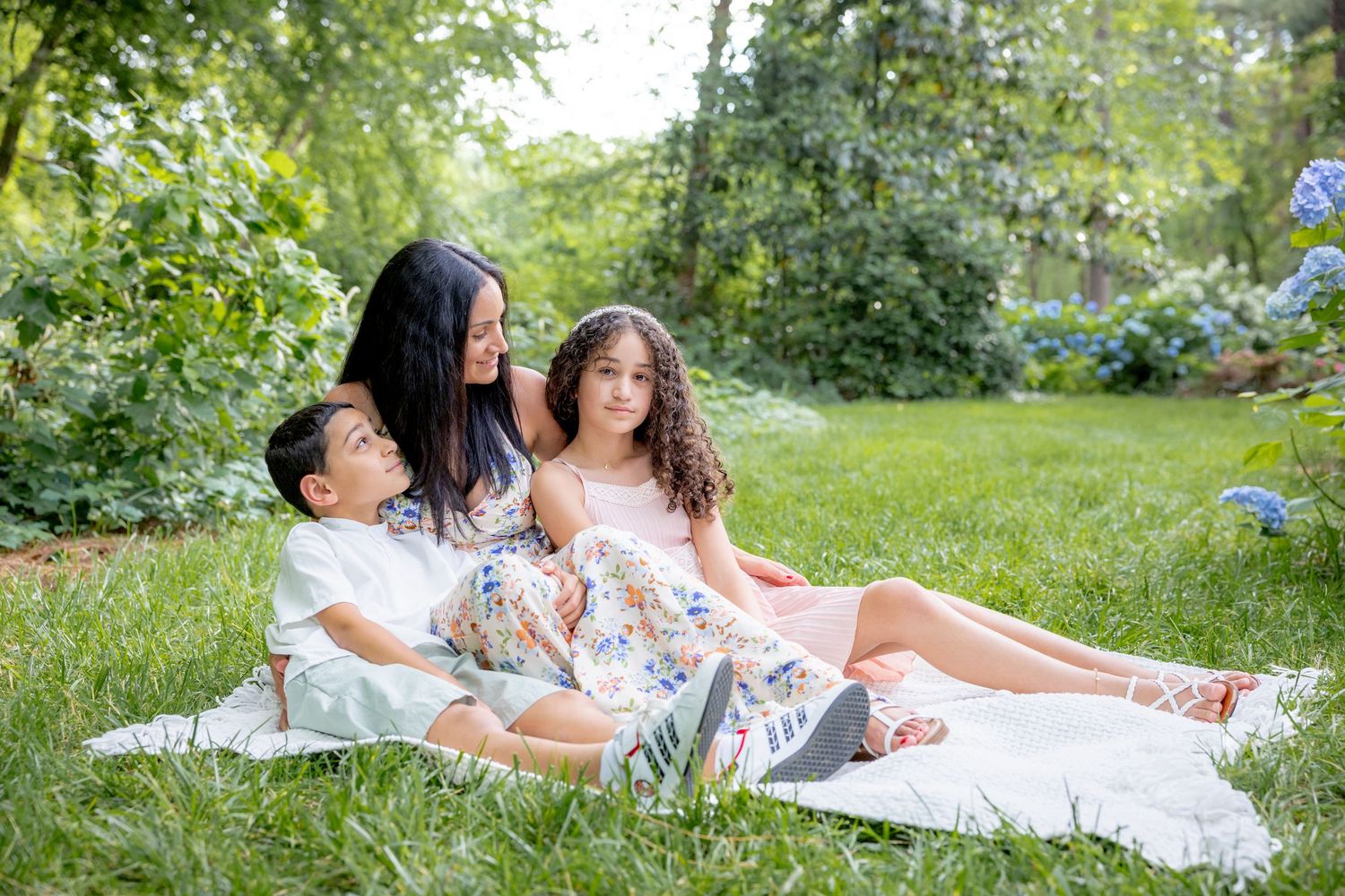 Family relaxing together on white blanket in lush garden setting at Glencairn Gardens in Rock Hill, SC.
