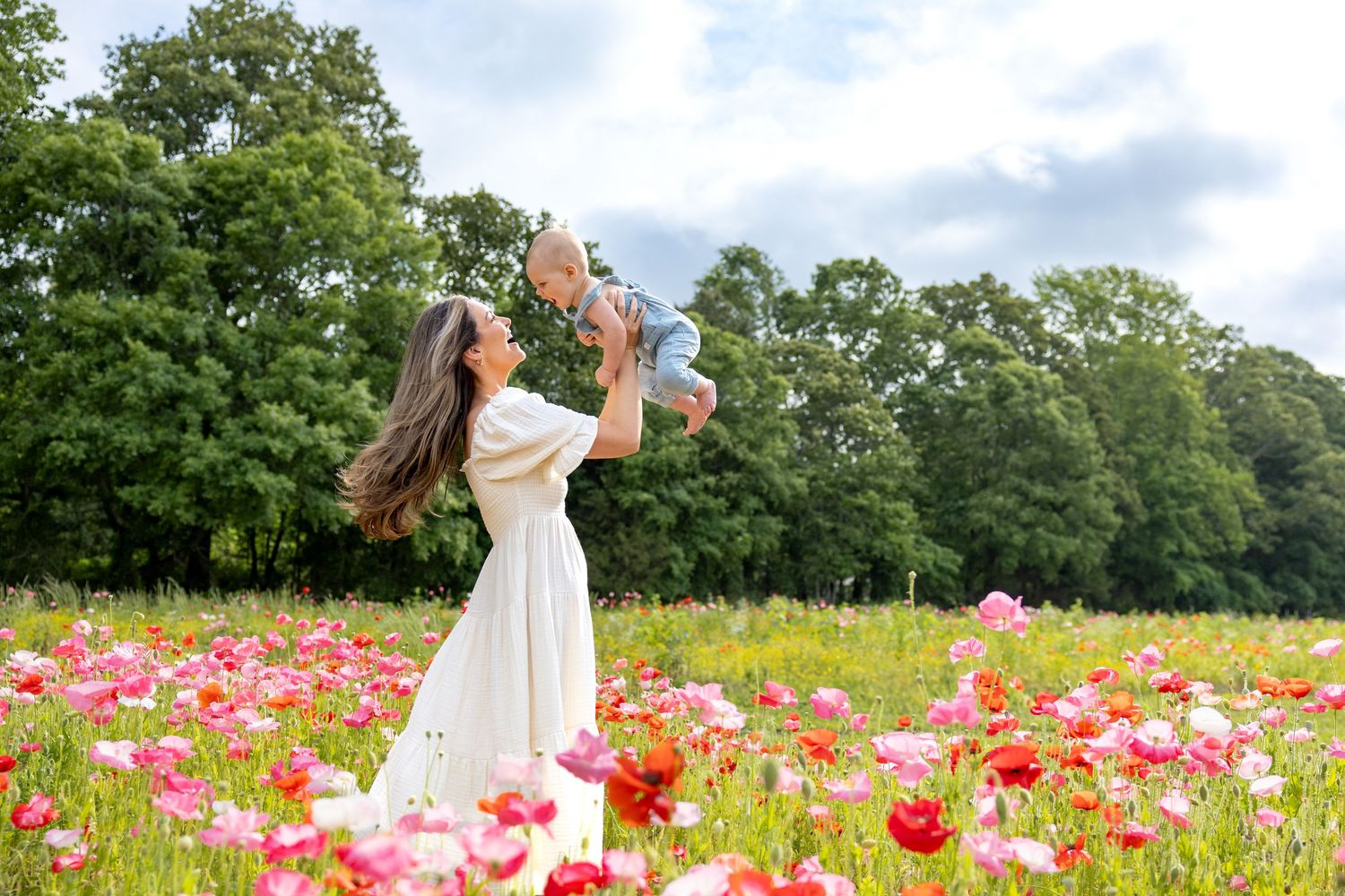 Beautiful scene of mom and baby in a blooming poppy field under summer clouds at Blue Hill Garden in Monroe, NC.
