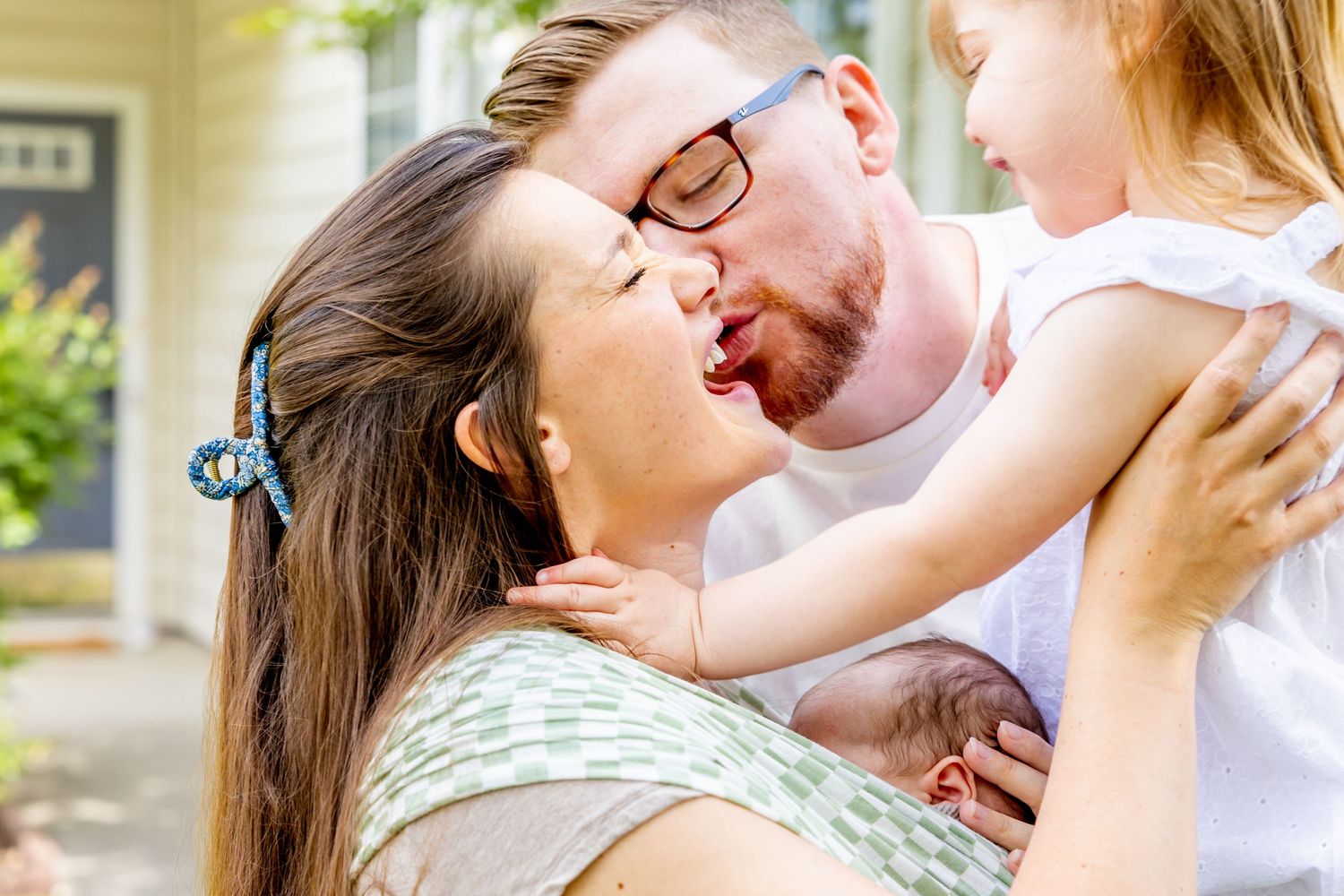 Family sharing loving embrace outdoors on front porch.