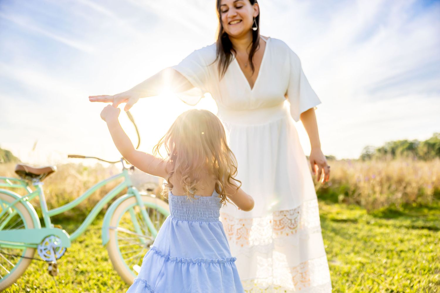 Dreamy summer portrait with soft white dresses against bright natural sunlight in a green field.