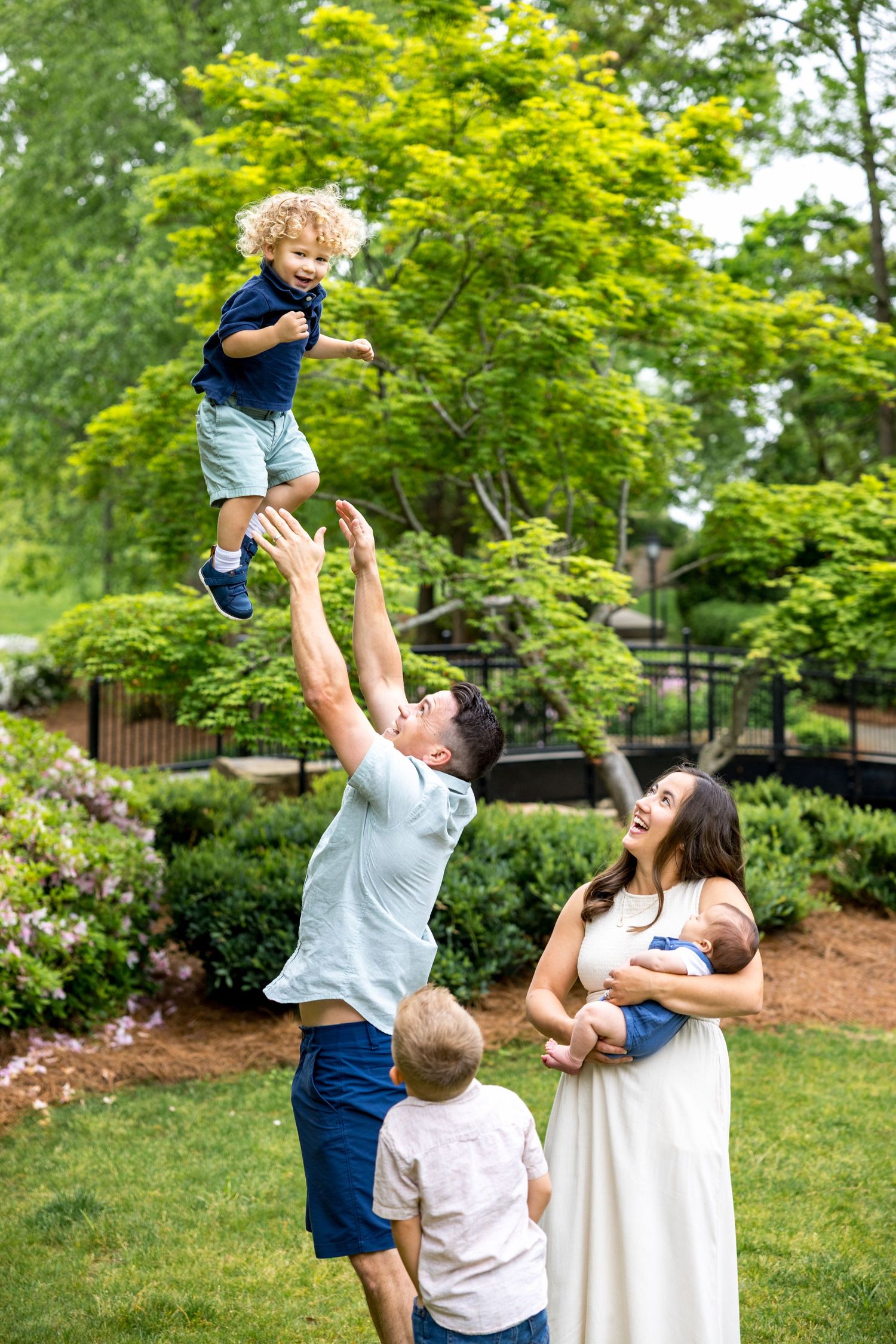 Playful family moment in a park with joyful tossing and catching motions.