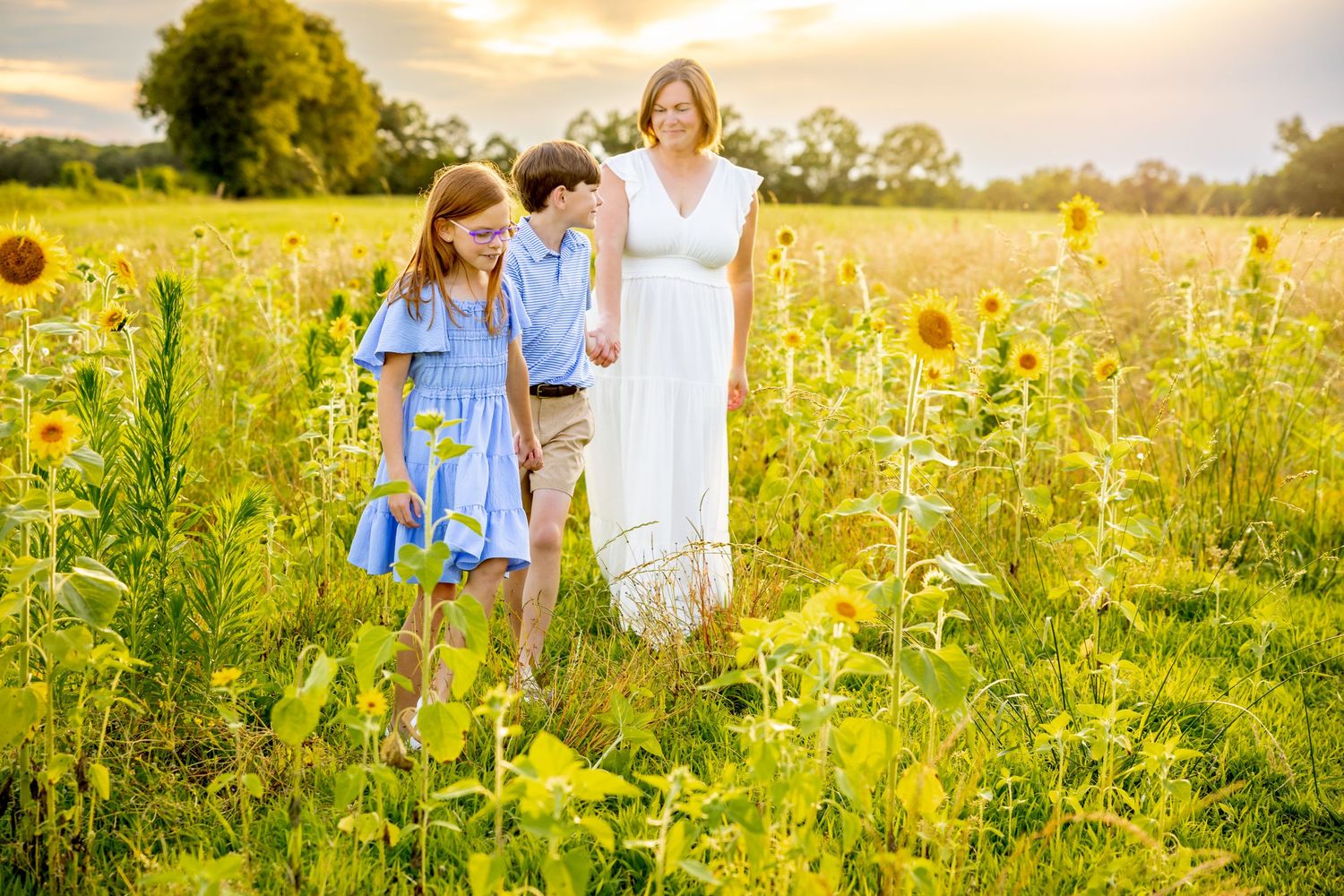 Family moment in wildflower meadow wearing white and blue outfits during golden hour at Blue Hill Garden in Monroe, NC.