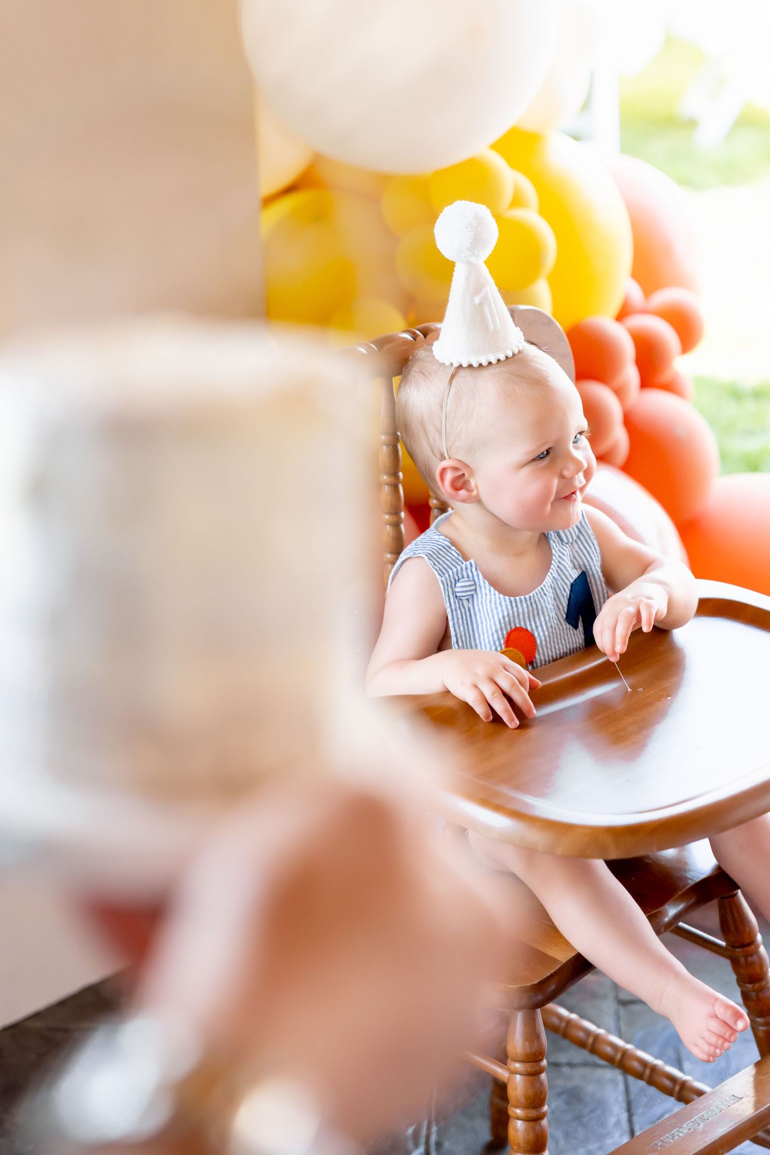 First birthday celebration setup with vintage high chair and festive balloon decorations.