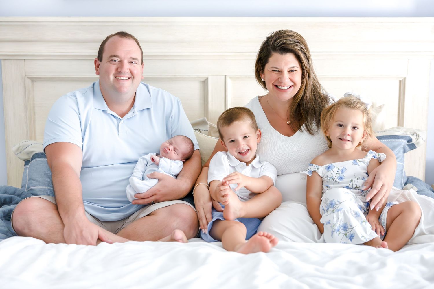Happy family with children relaxing together on white bed.
