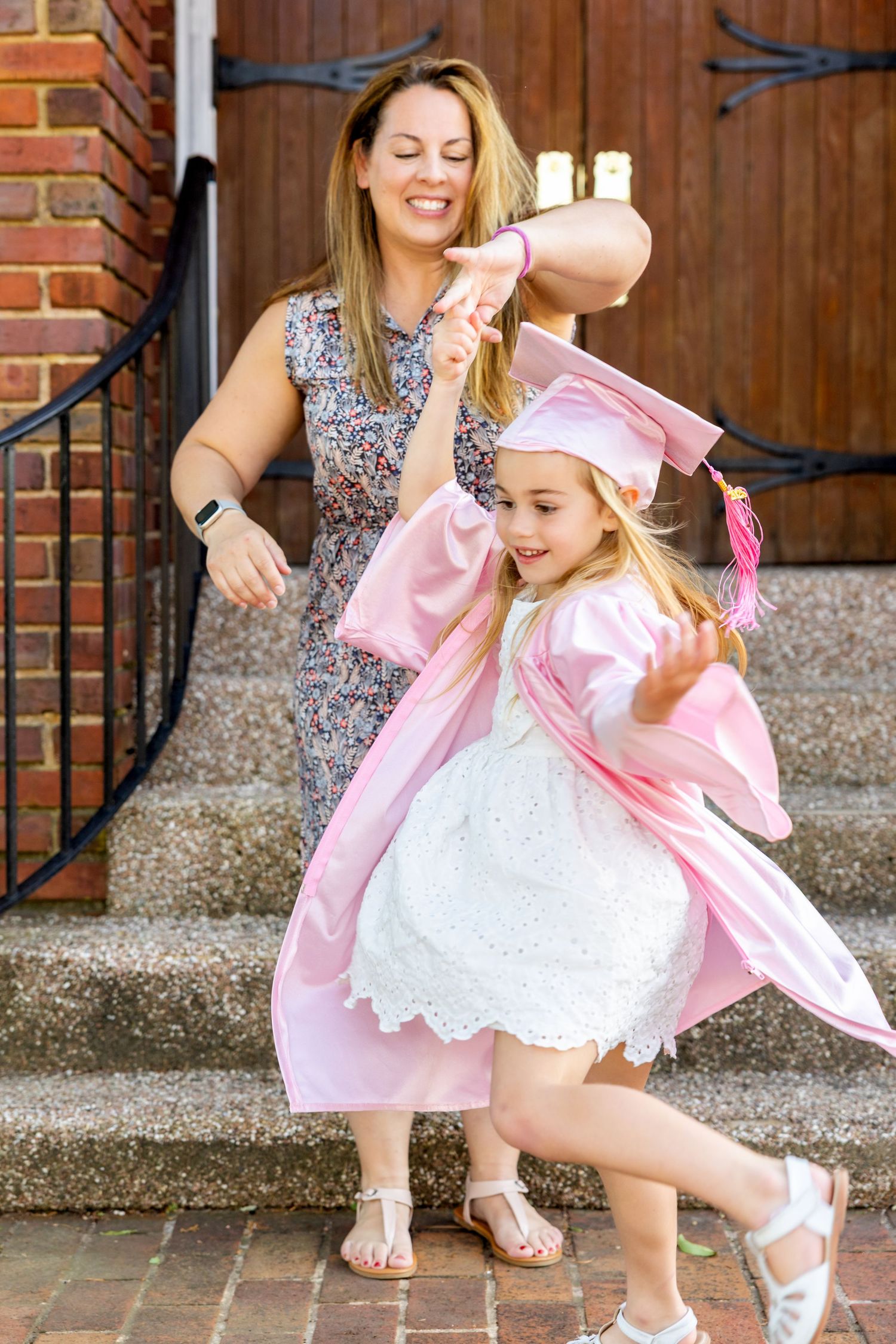 Dancing sequence showing joyful movements in pink and white outfits on brick church steps celebrating preschool graduation.