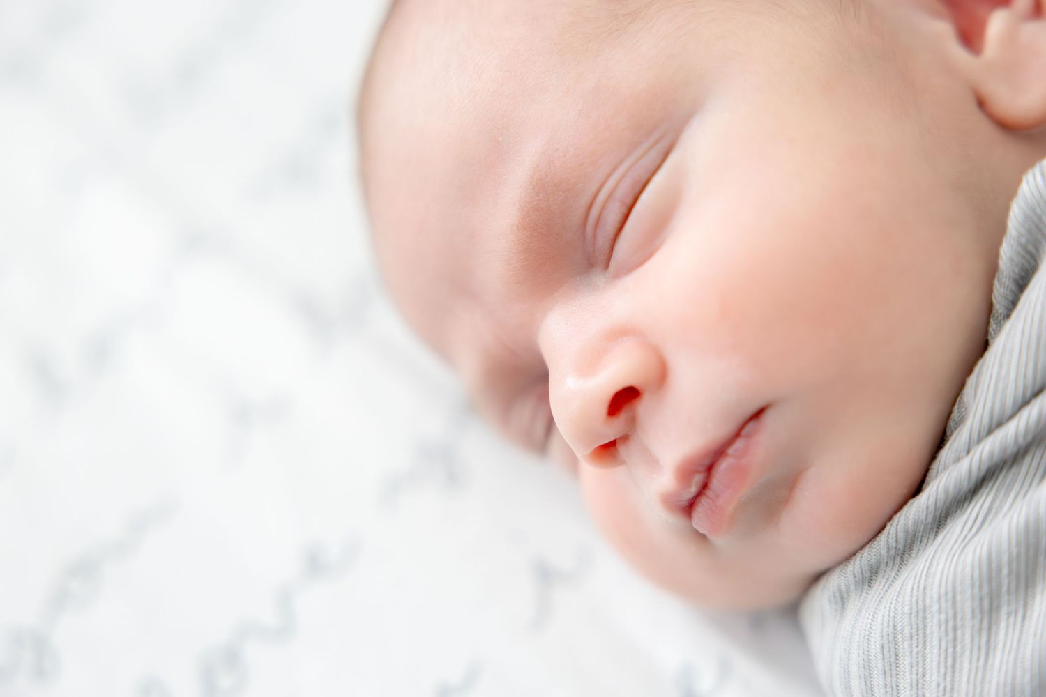 Gentle profile view of sleeping infant against white background.