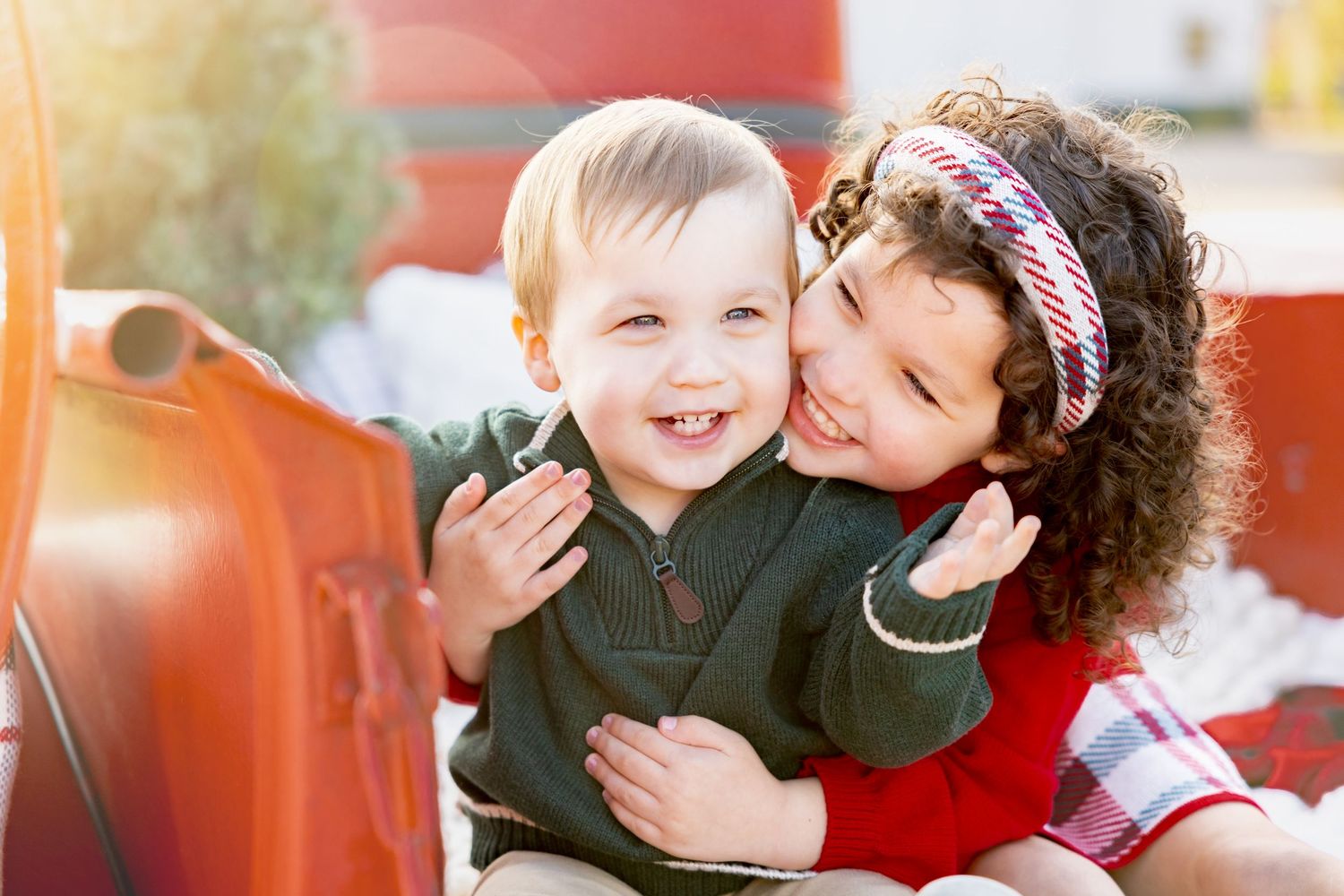 Sweet candid moment captures children's genuine laughter in back of vintage truck.