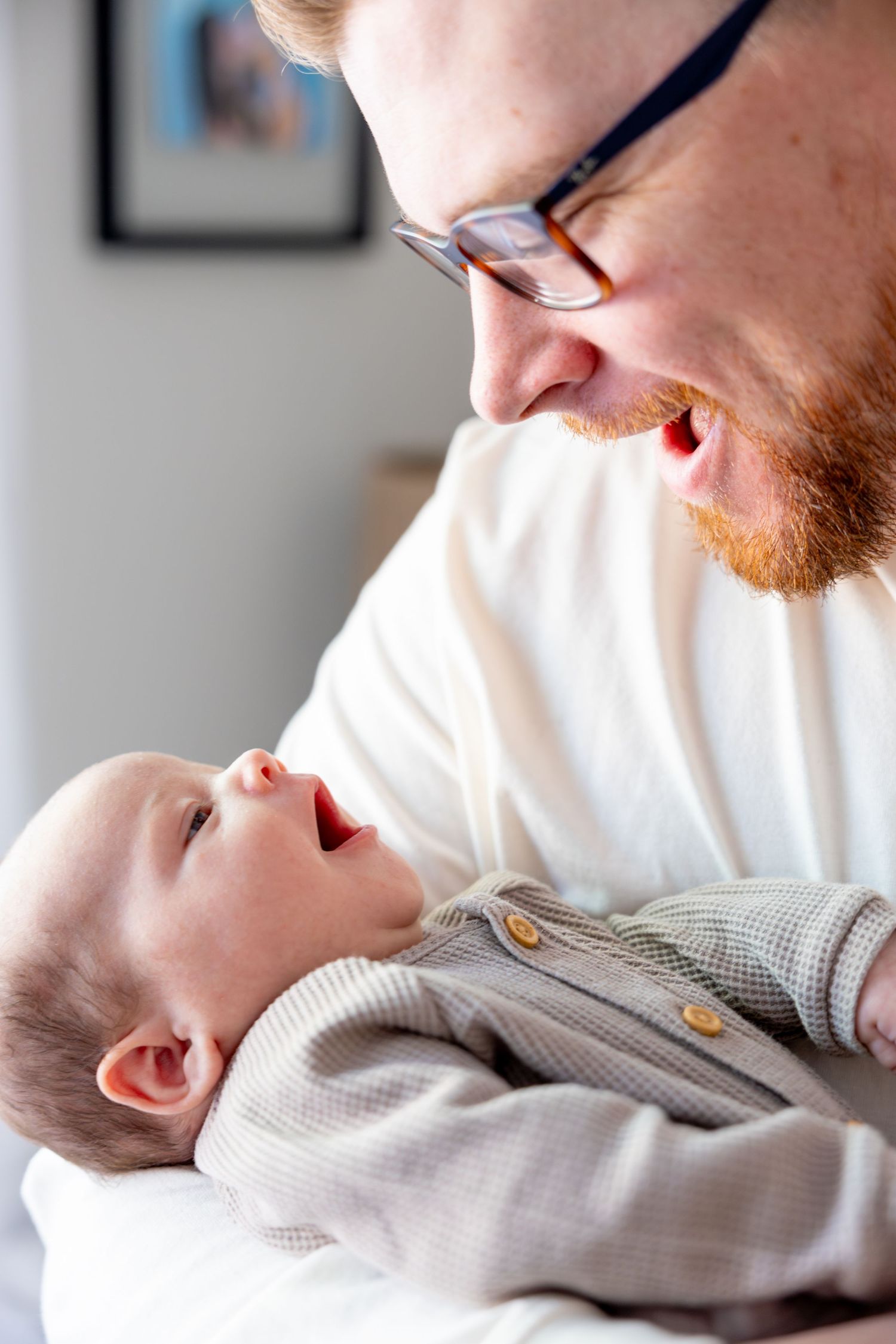 Parent and baby sharing tender moment in gray sweaters against white background.