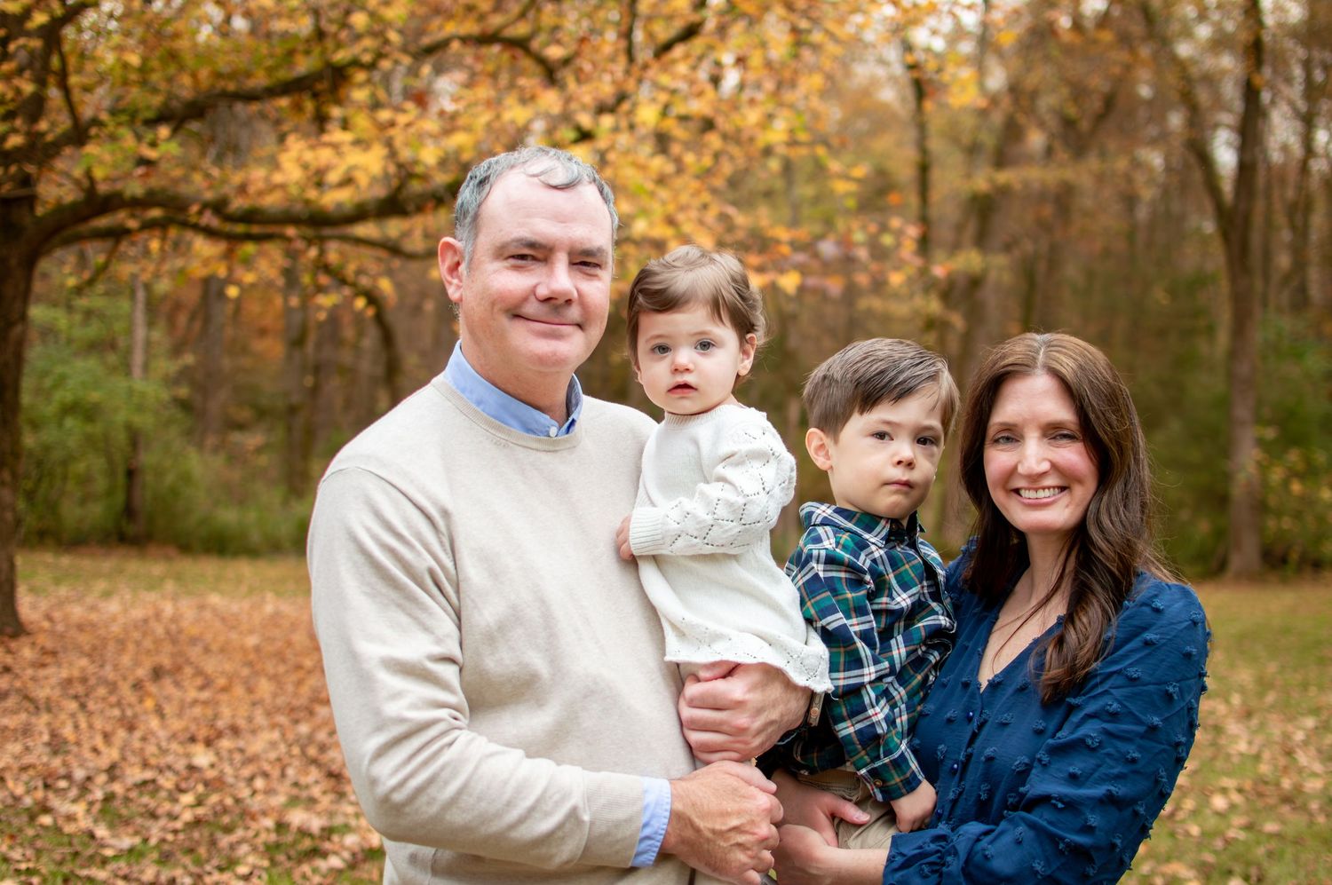 Family in coordinating outfits poses together against autumn foliage in an outdoor setting at Westminster Park in Rock Hill, SC.