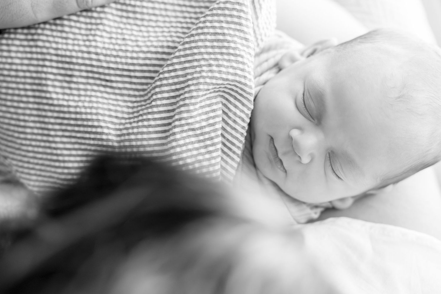Peaceful sleeping baby in soft grey lighting with delicate features.