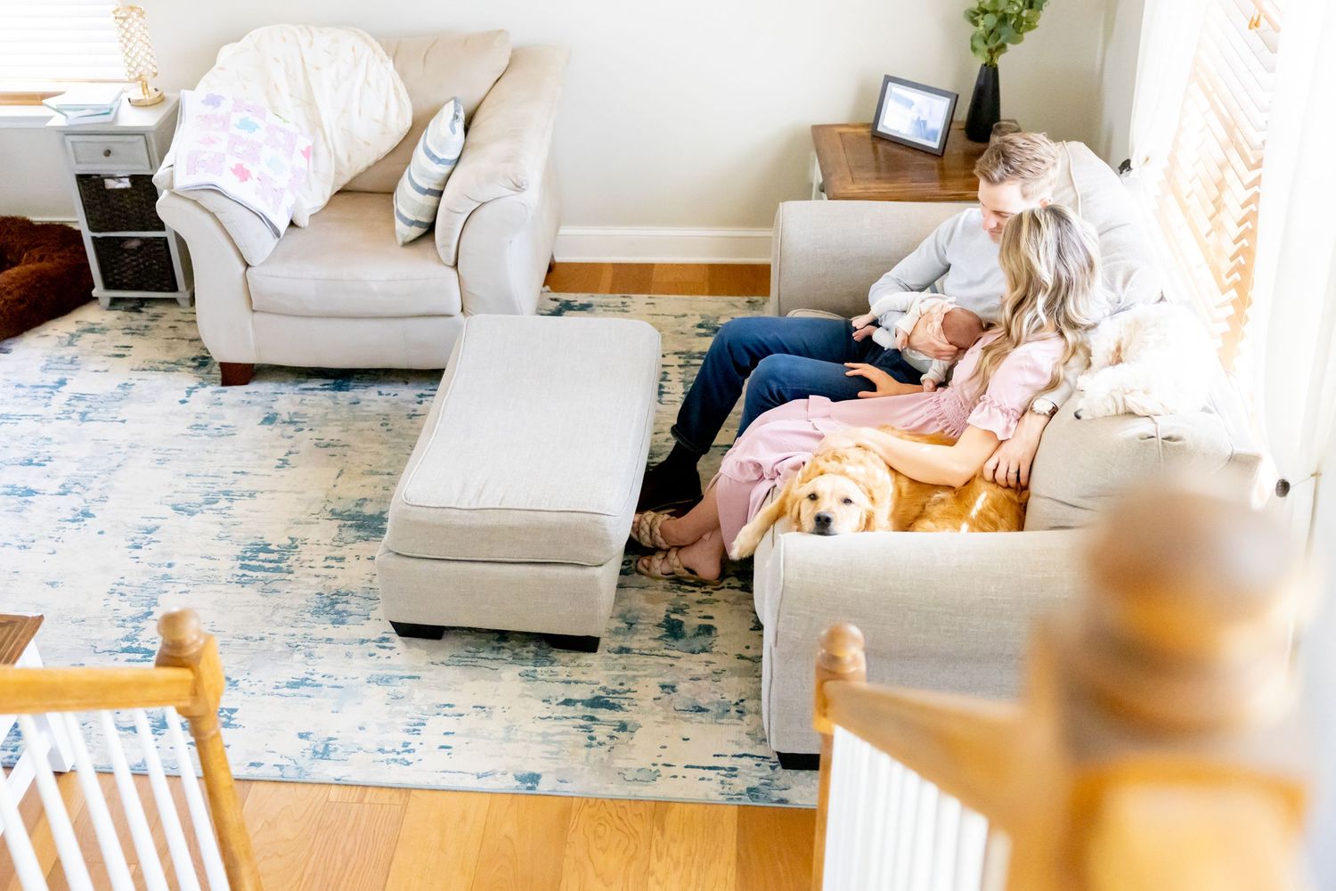 Cozy living room scene with white furniture and a golden retriever during a family photoshoot.