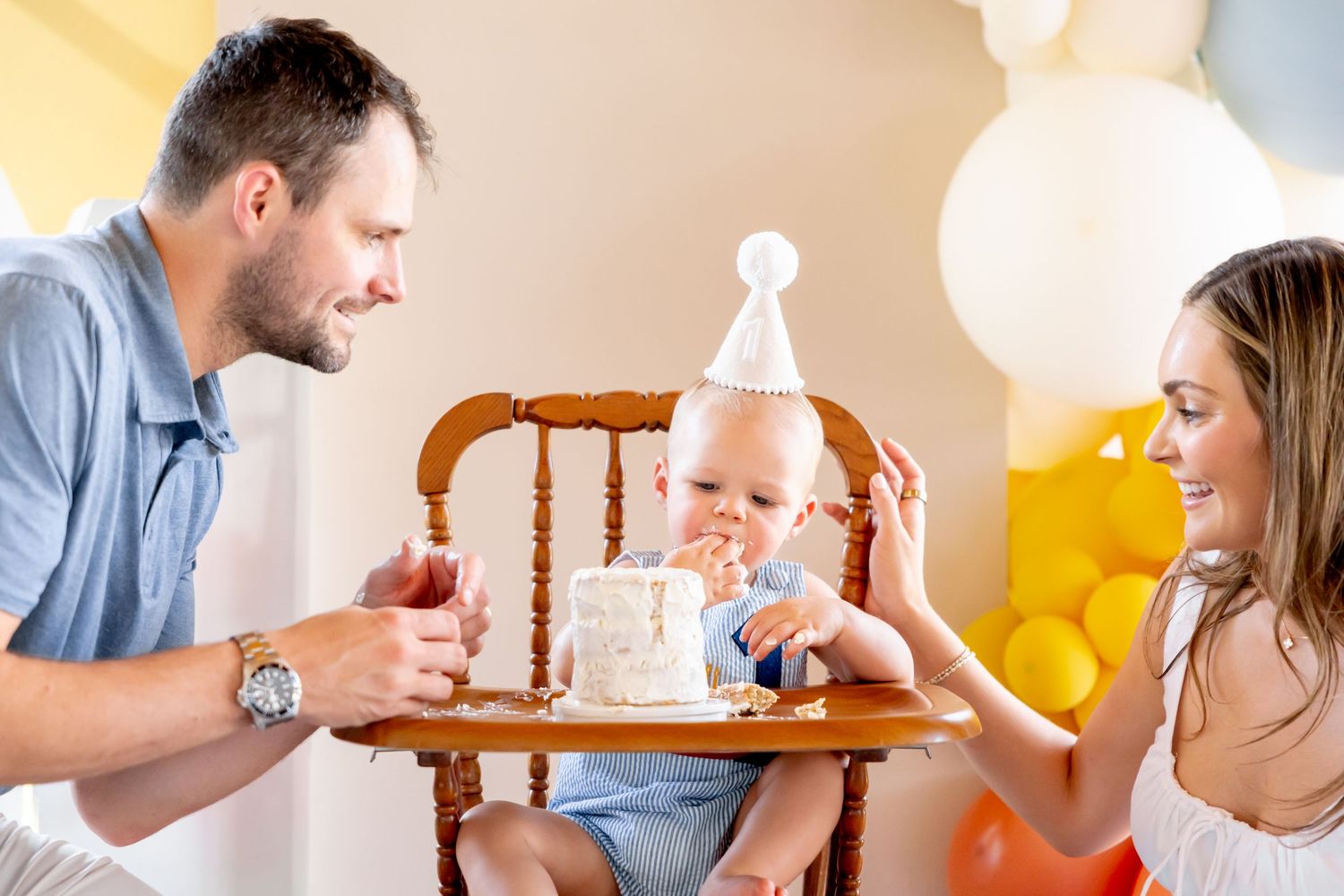 First birthday cake smash celebration with vintage high chair and balloon decorations.