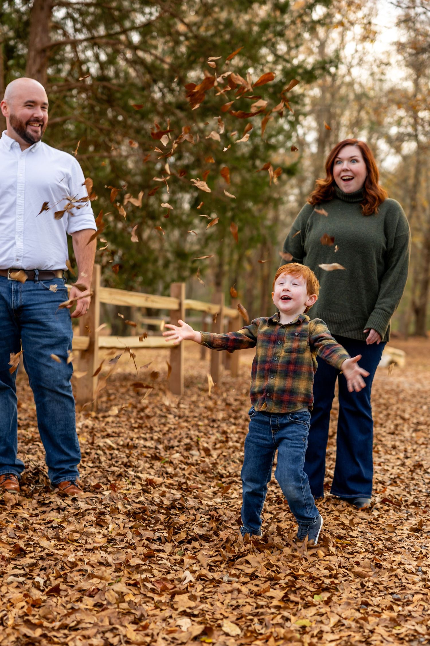A playful family scene in autumn woods with falling leaves and joy-filled expressions.