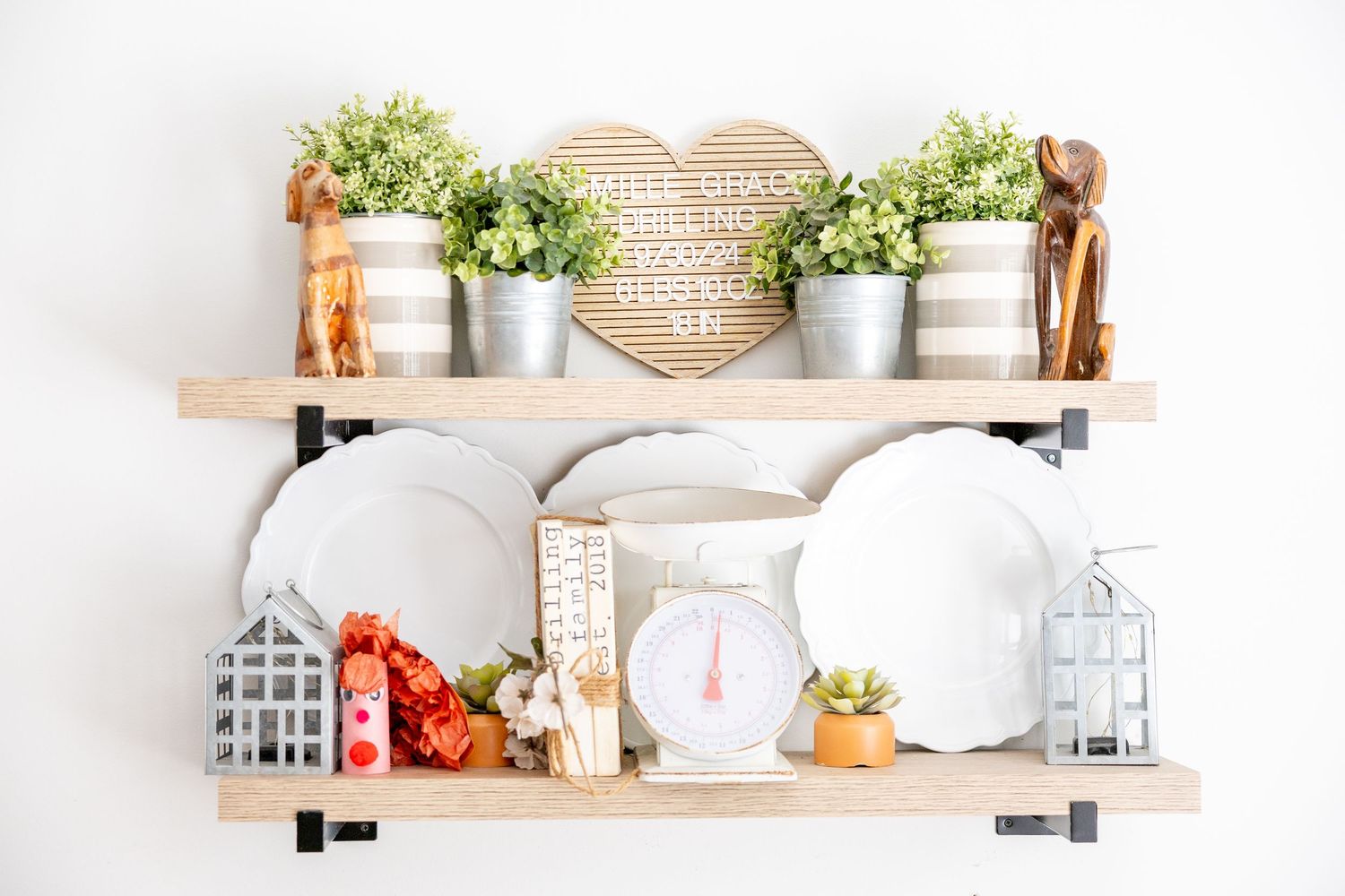 Farmhouse style floating shelves with white dishes, woven baskets and greenery decor.