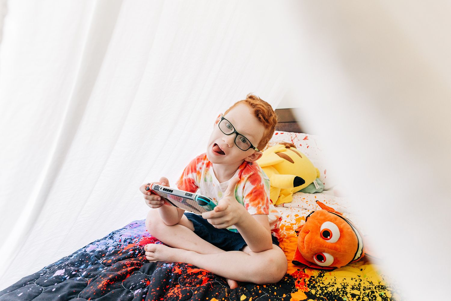 Baby lounging with colorful stuffed animal toys on white bedding.
