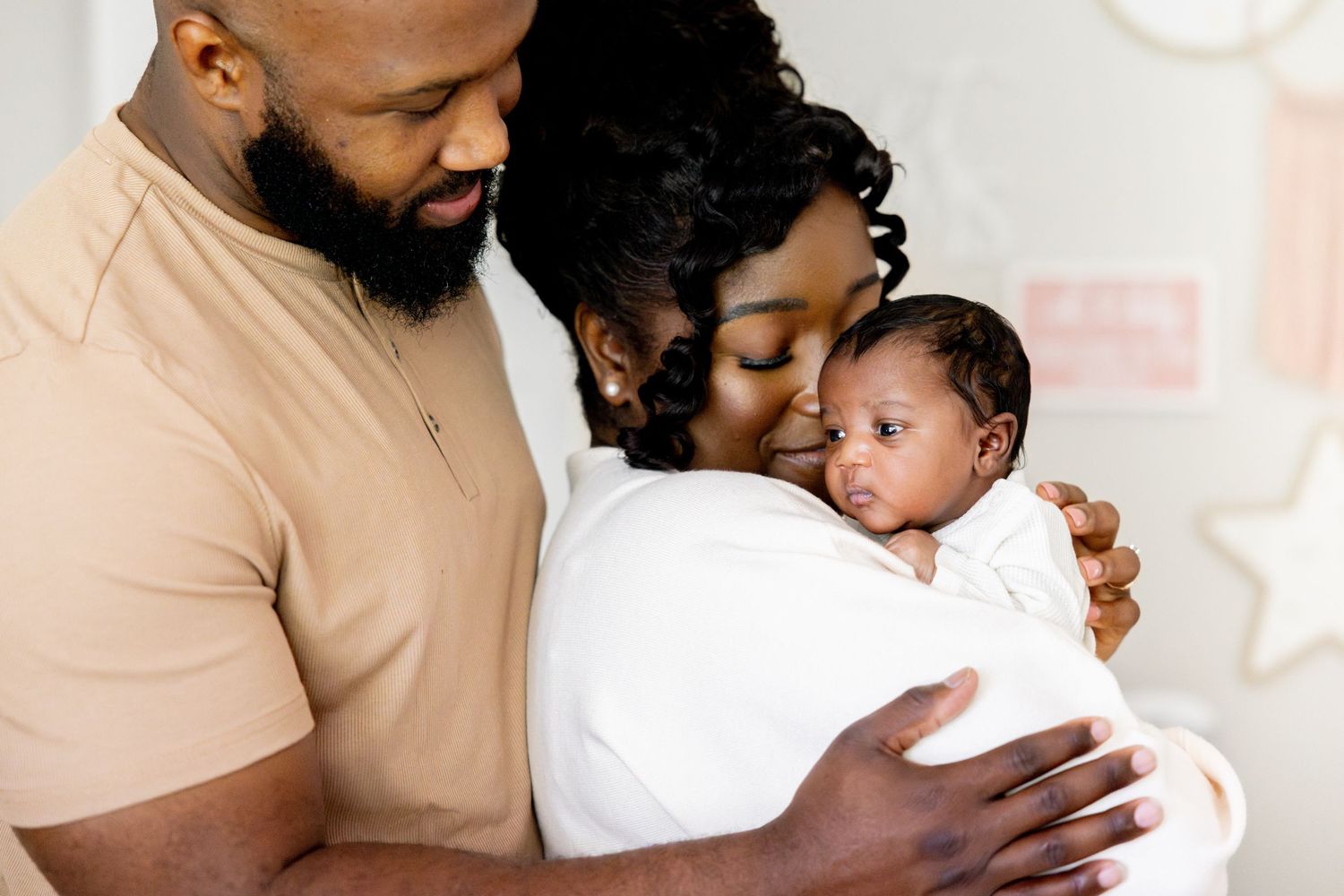 Family wearing white and neutral tones shares tender moments together.