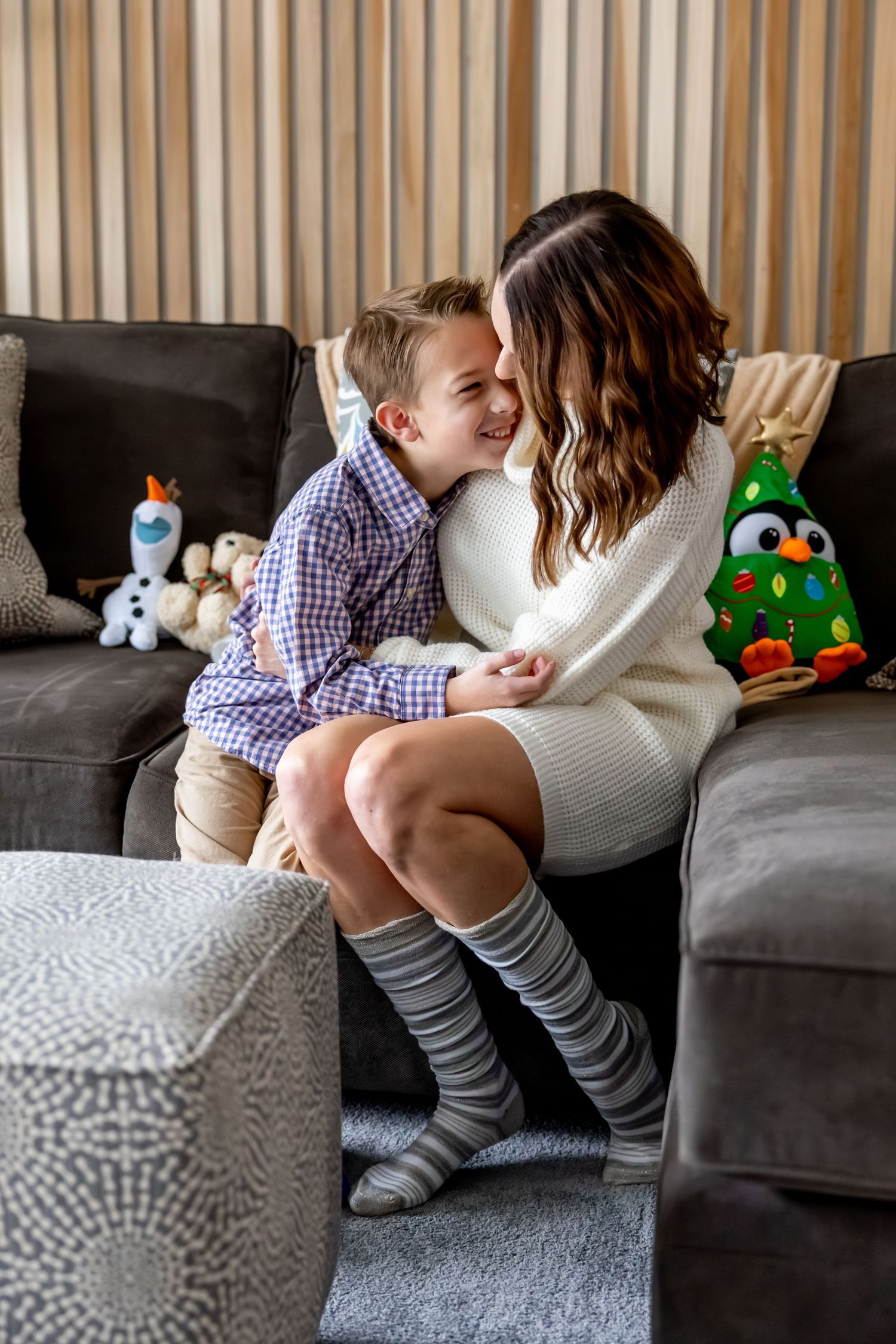 Tender moment shared on a grey couch with stuffed toys in the background.