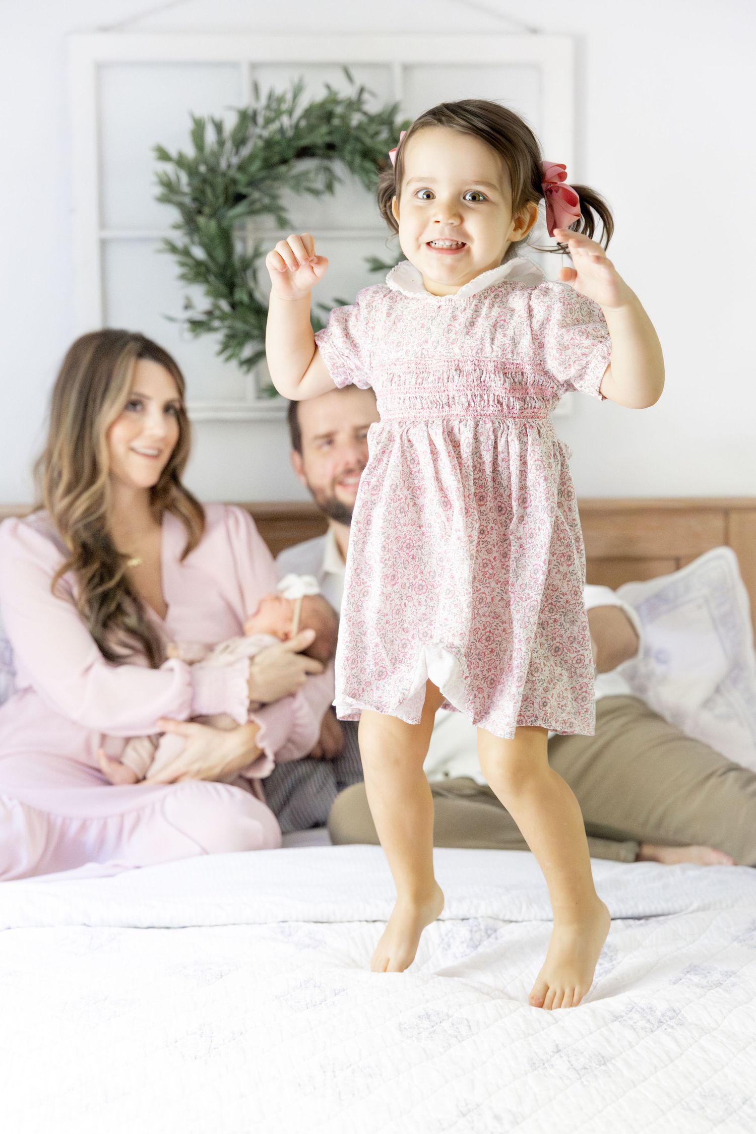 Playful scene on white bedding with pink floral dress and natural lighting.