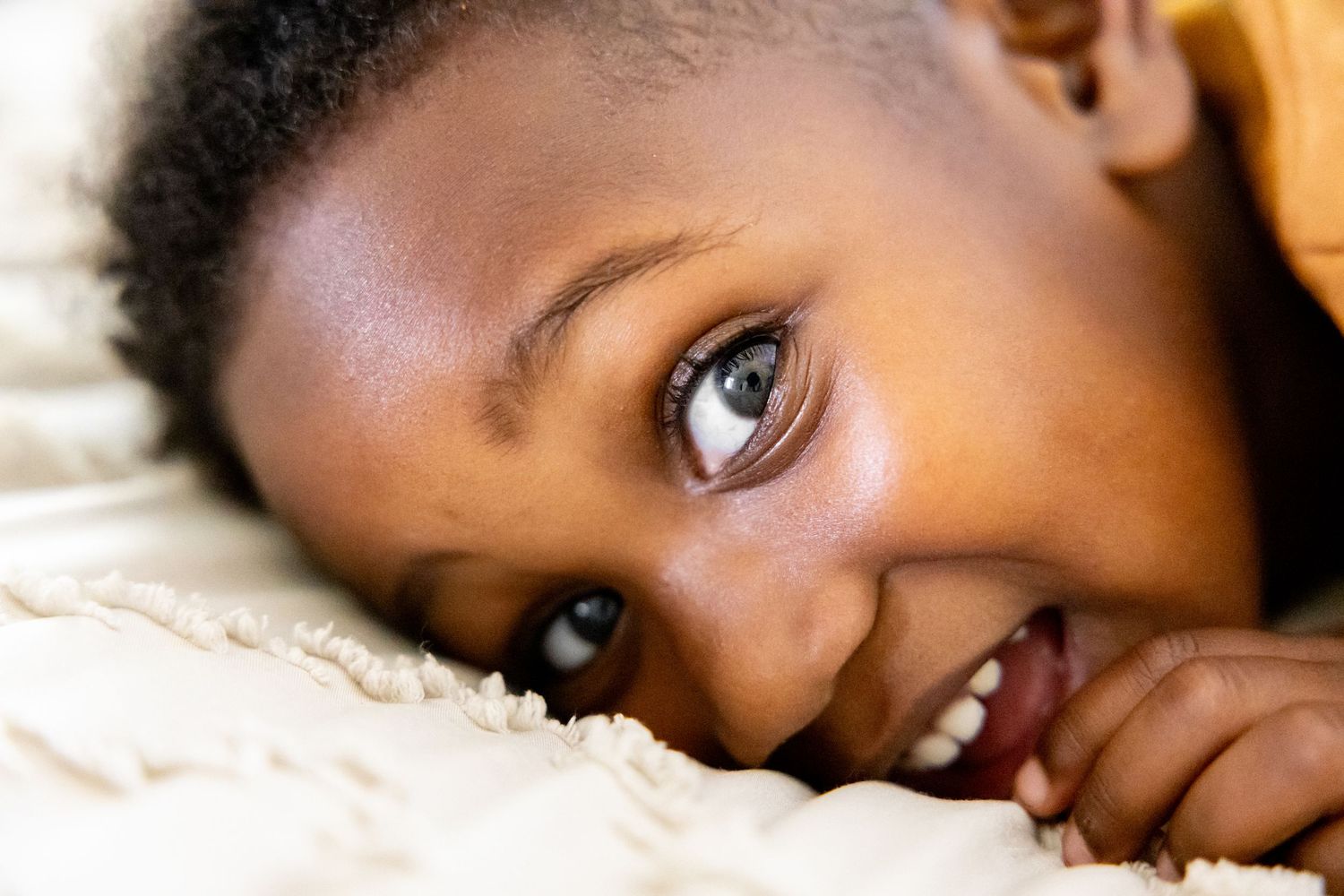 Close-up of expressive brown eyes and facial features against white bedding.