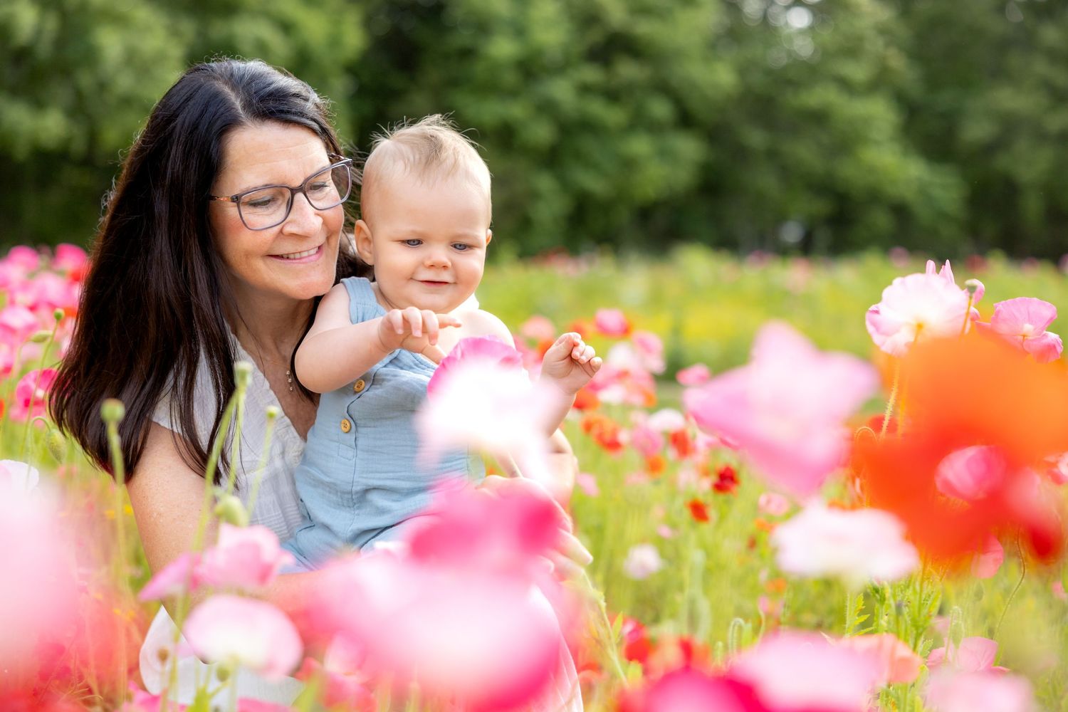 Mother and baby enjoying a sunny day in a vibrant field of pink and orange wildflowers at Blue Hill Garden in Monroe, NC.