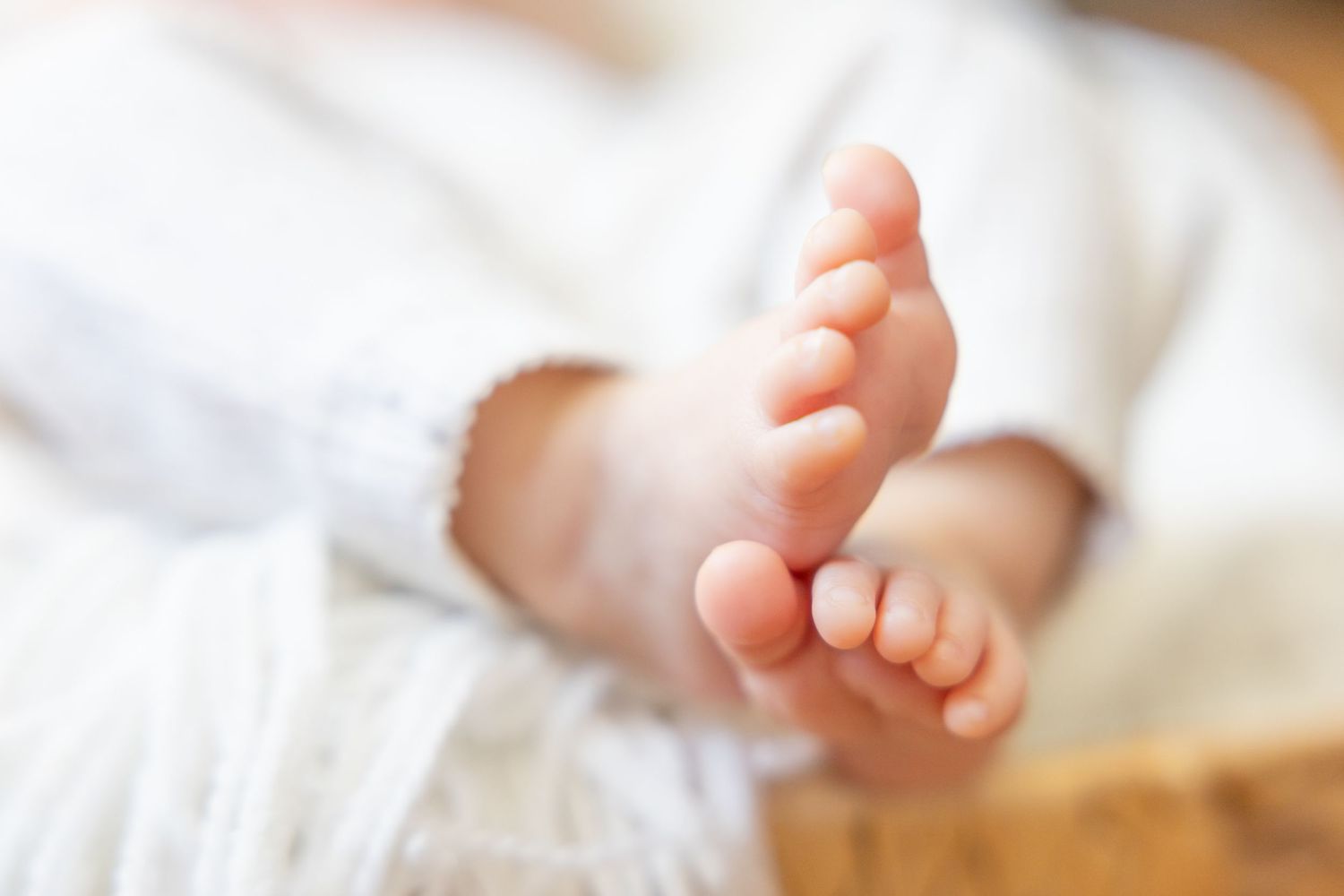 Close-up of tiny baby feet against soft white bedding.