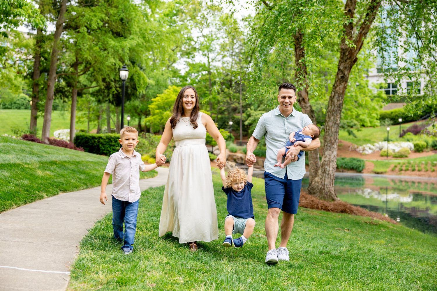 Family walking together on a winding path through a peaceful park landscape.