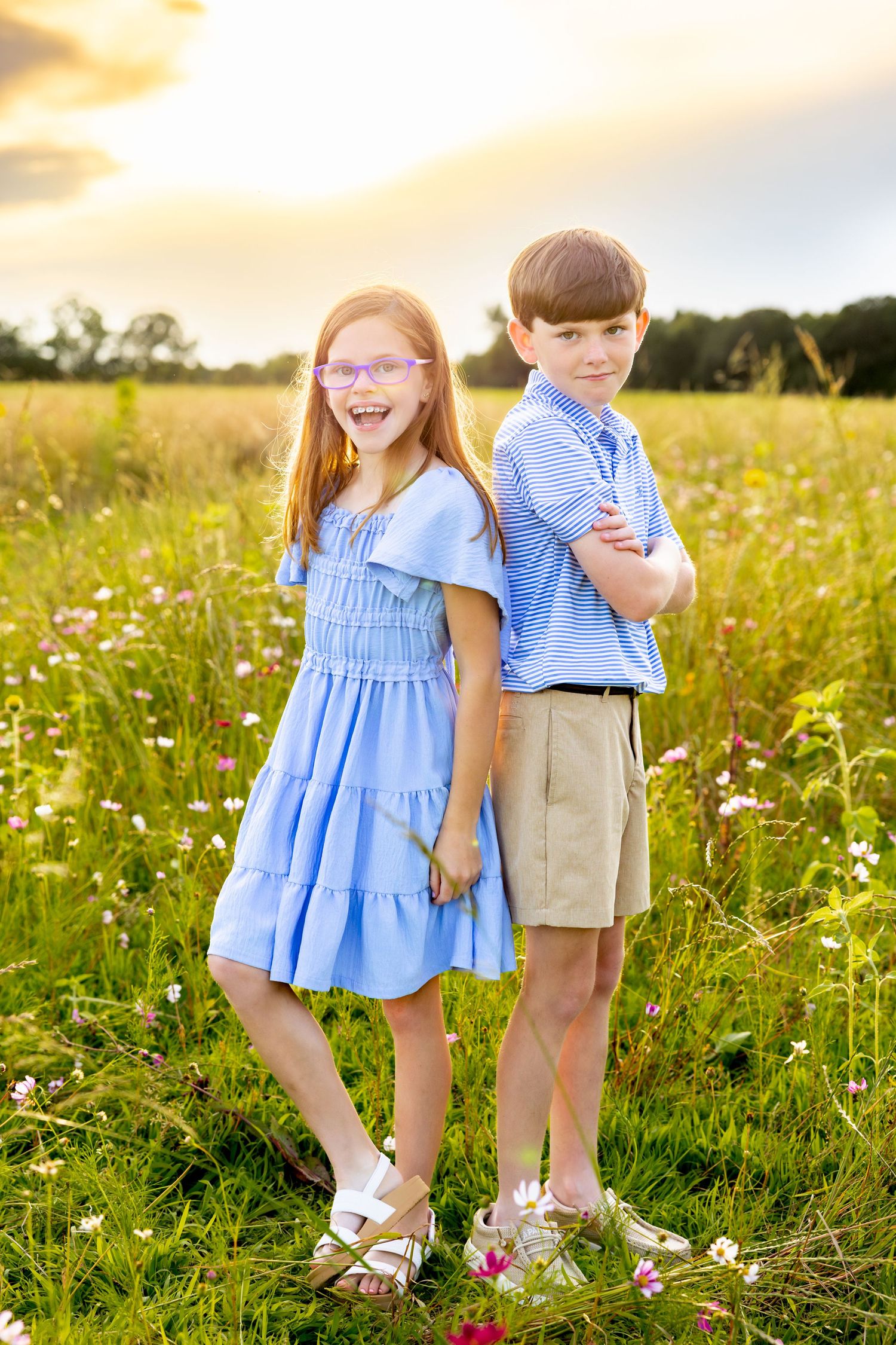 Two children standing back-to-back in a flowering meadow wearing coordinating blue outfits at Blue Hill Garden in Monroe, NC.