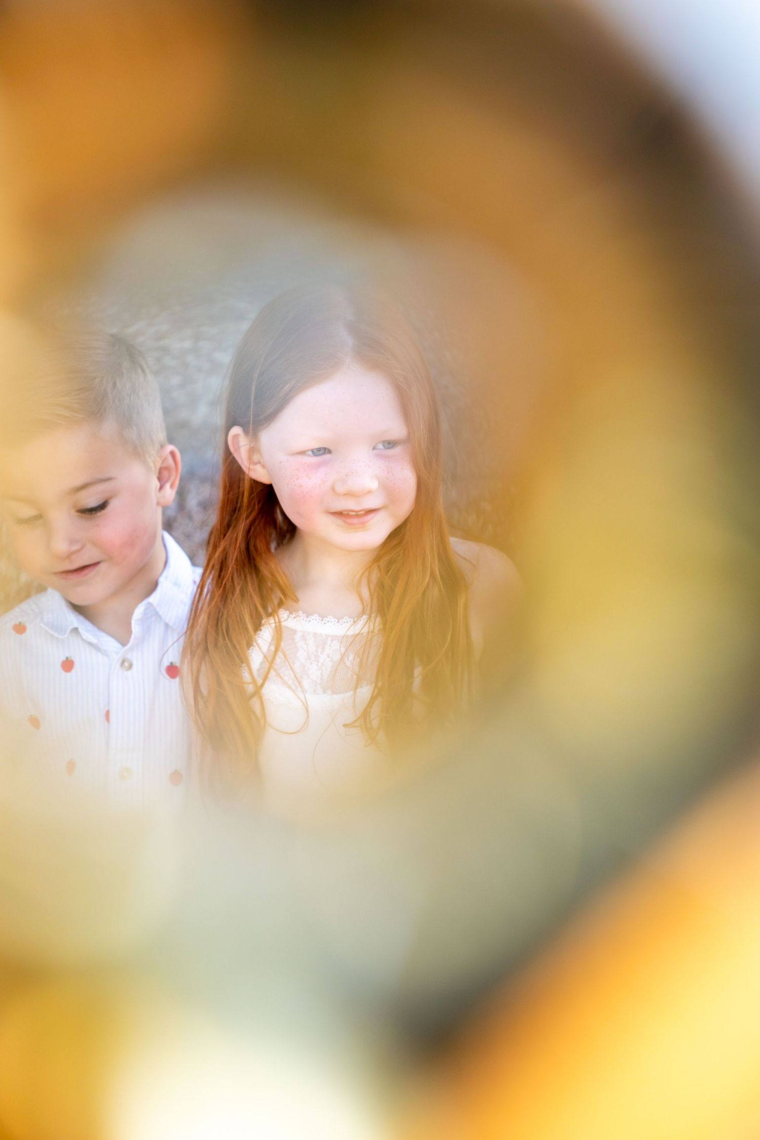 A soft focus portrait shot of preschool graduate through a golden letter balloon with warm golden lighting.