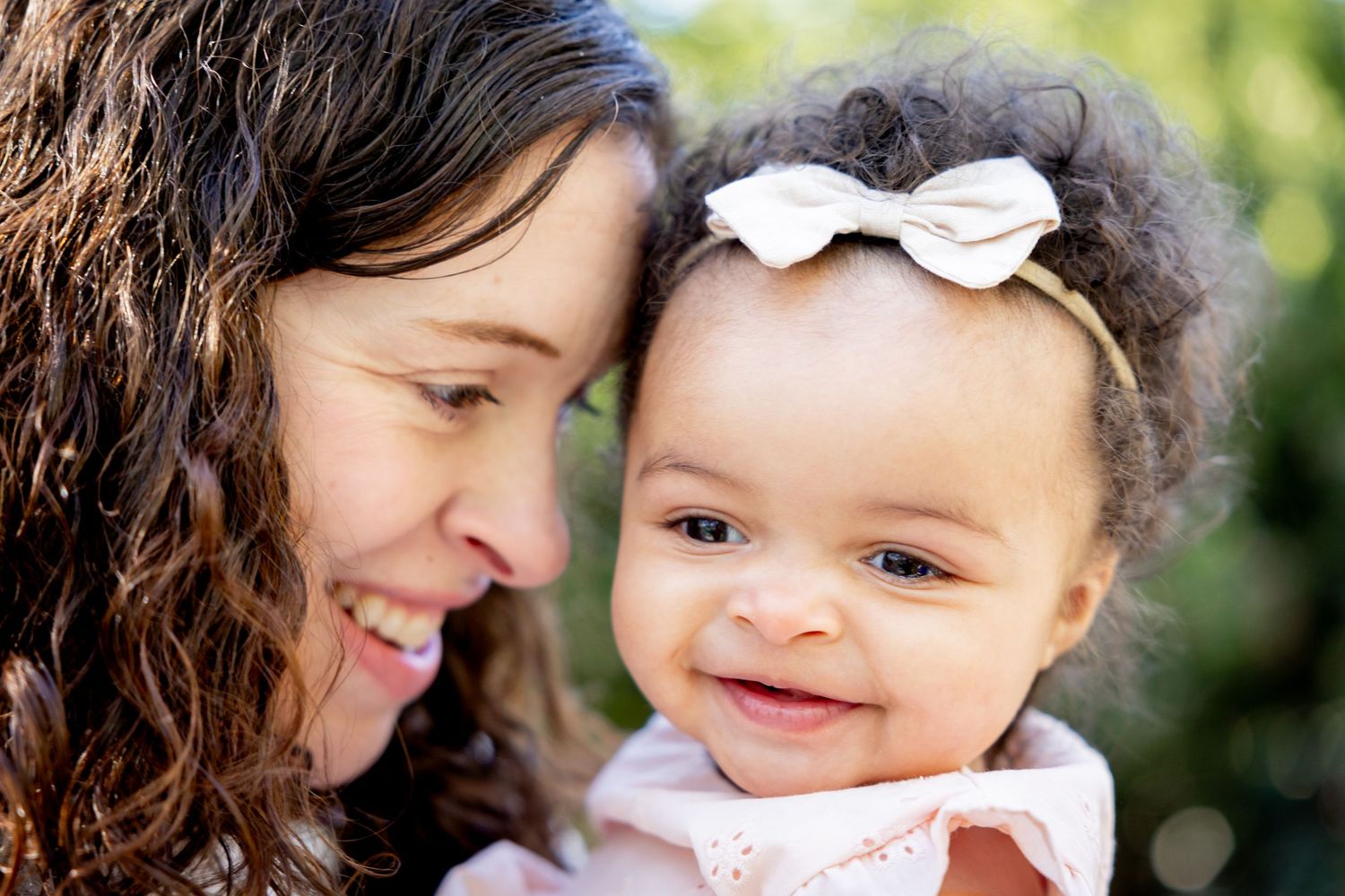 A sweet moment captured of shared smiles and bonding against a soft natural bokeh background.