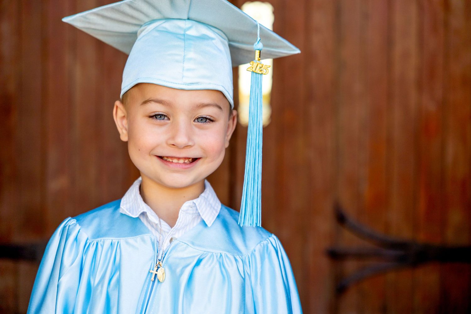 A kindergarten graduate in light blue cap and gown.