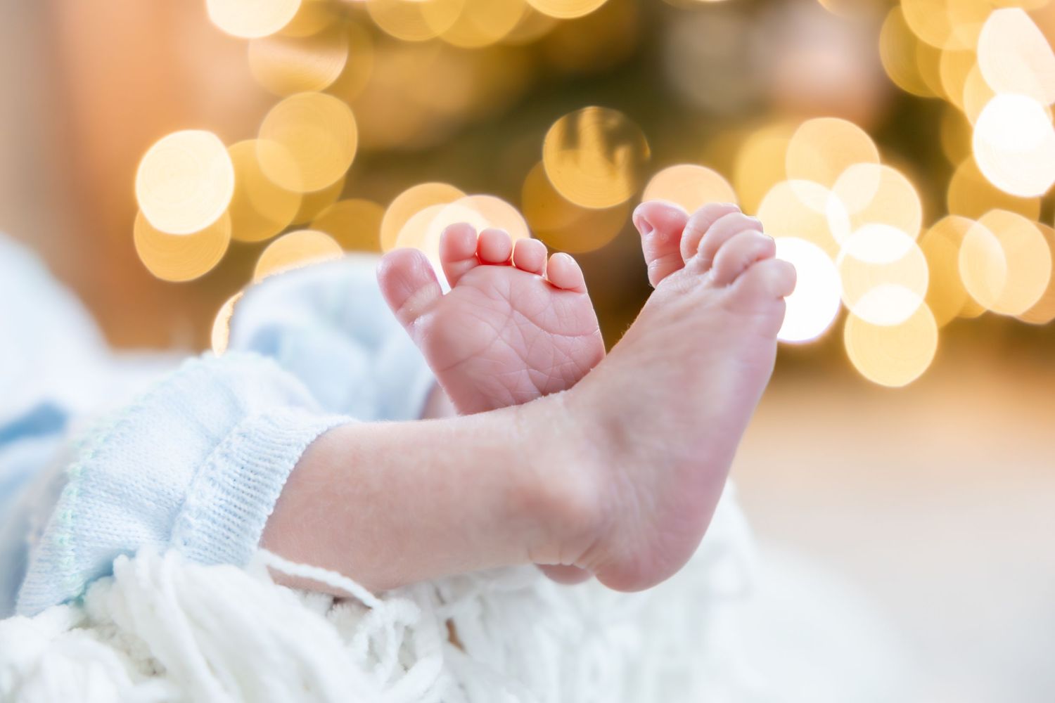 Tiny baby feet illuminated by soft bokeh lights in the background.