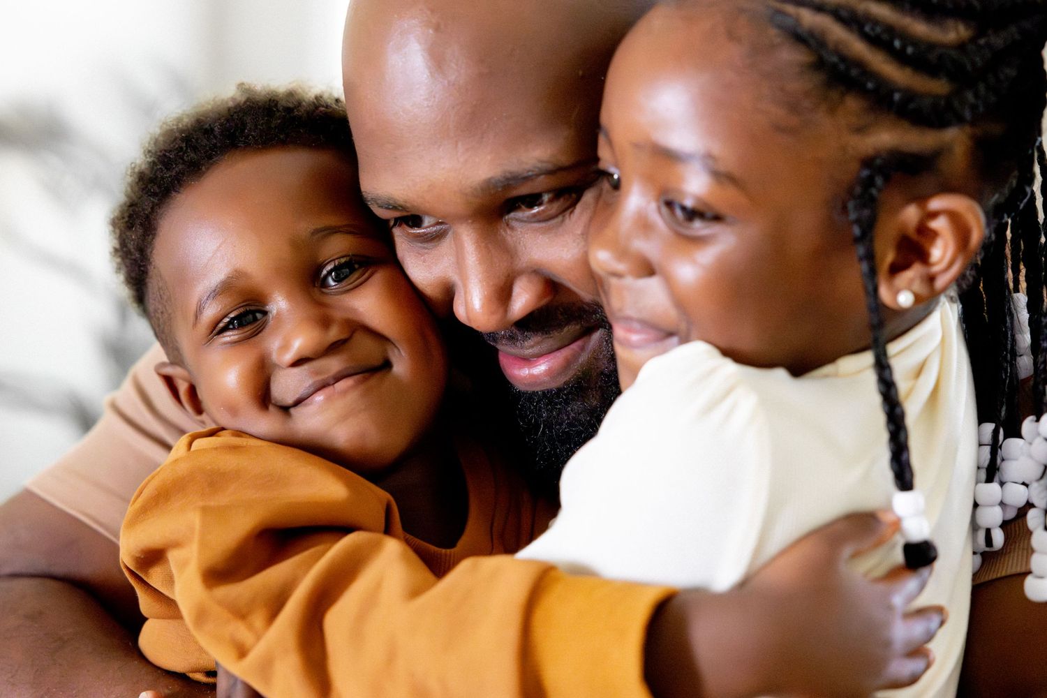 Sweet family cuddles and laughter on bed with soft white linens.