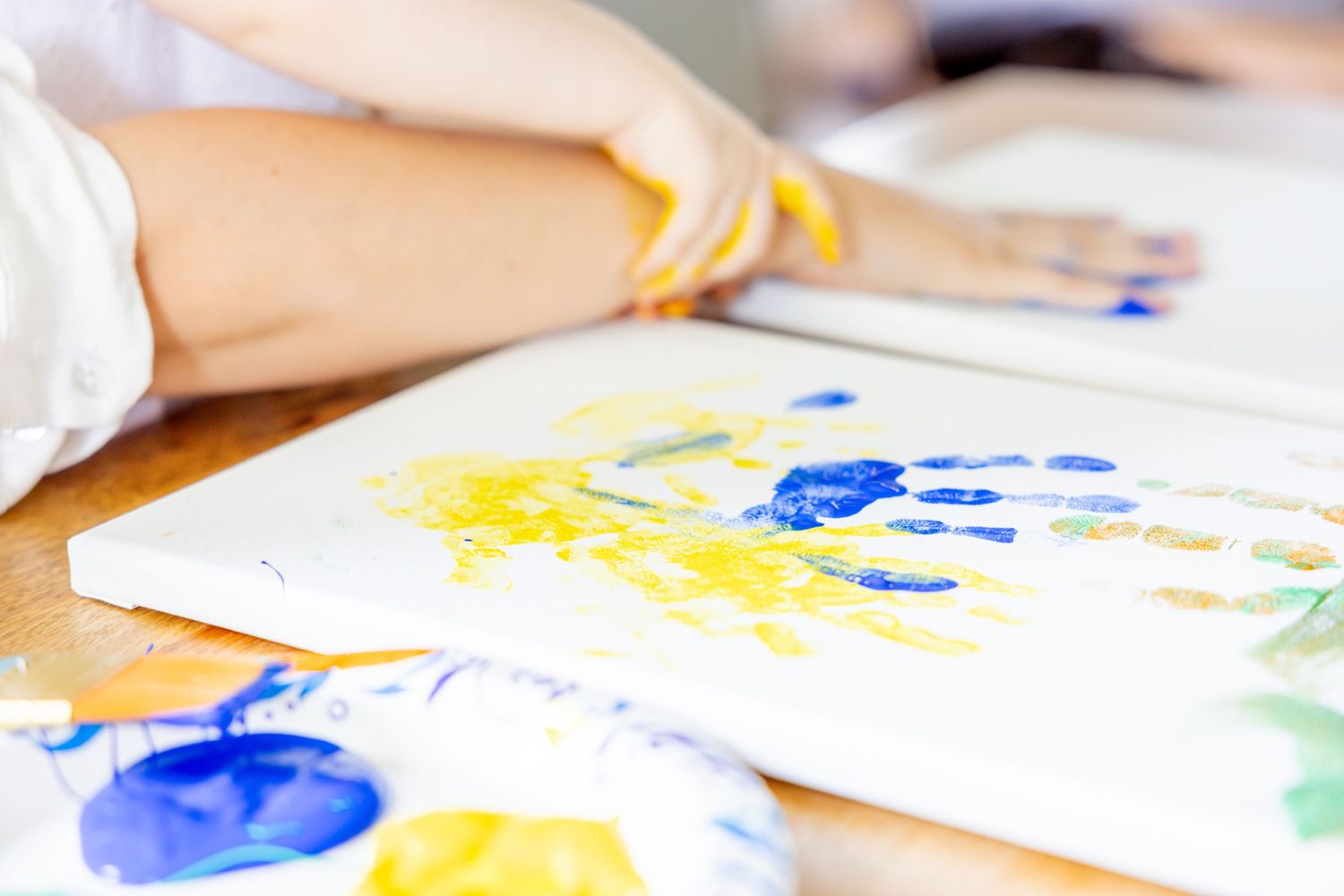 Watercolor painting in progress with vibrant blue and yellow paint strokes on white paper.