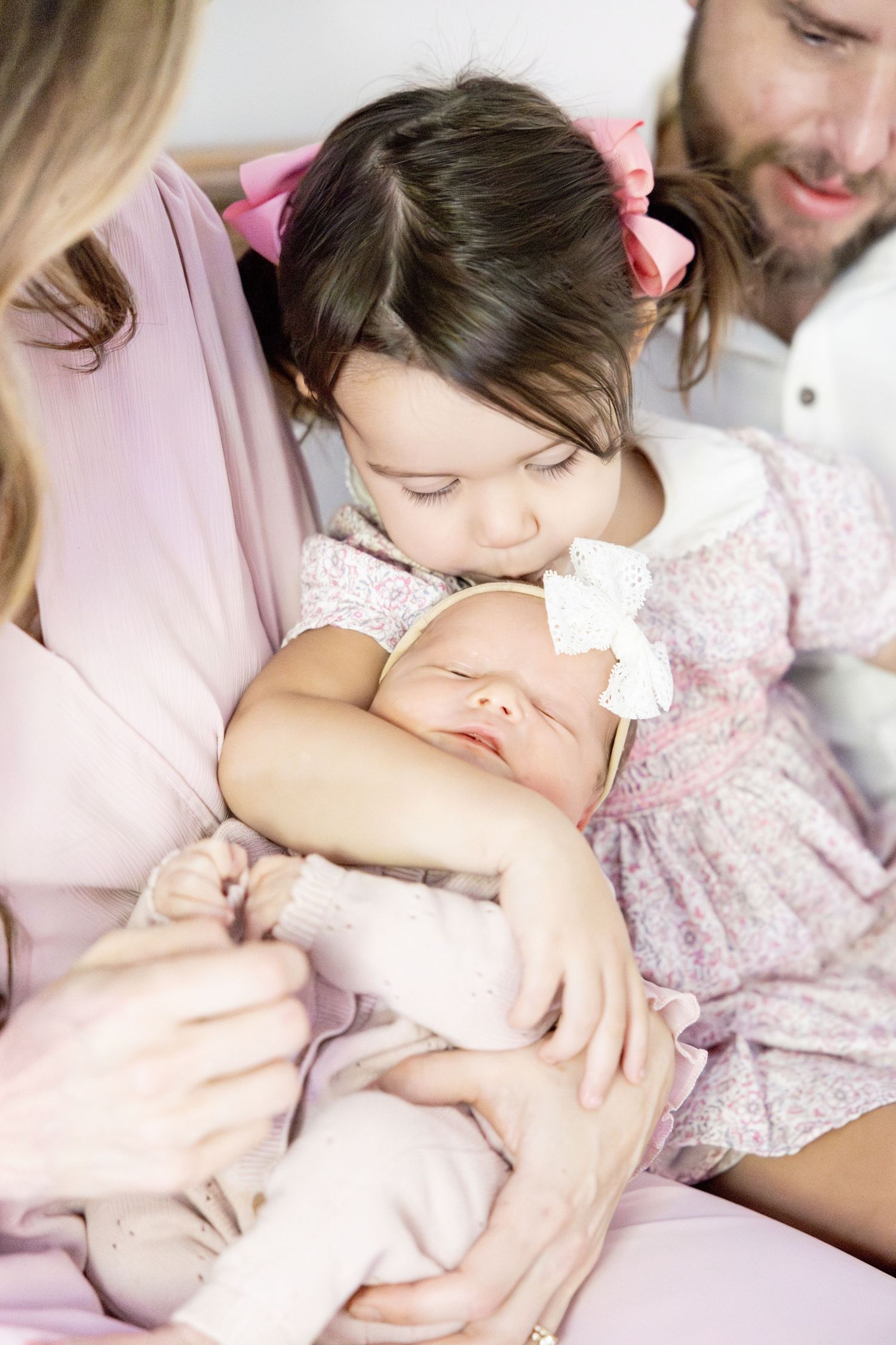 Family bonding moment on bed with pink and white decor.