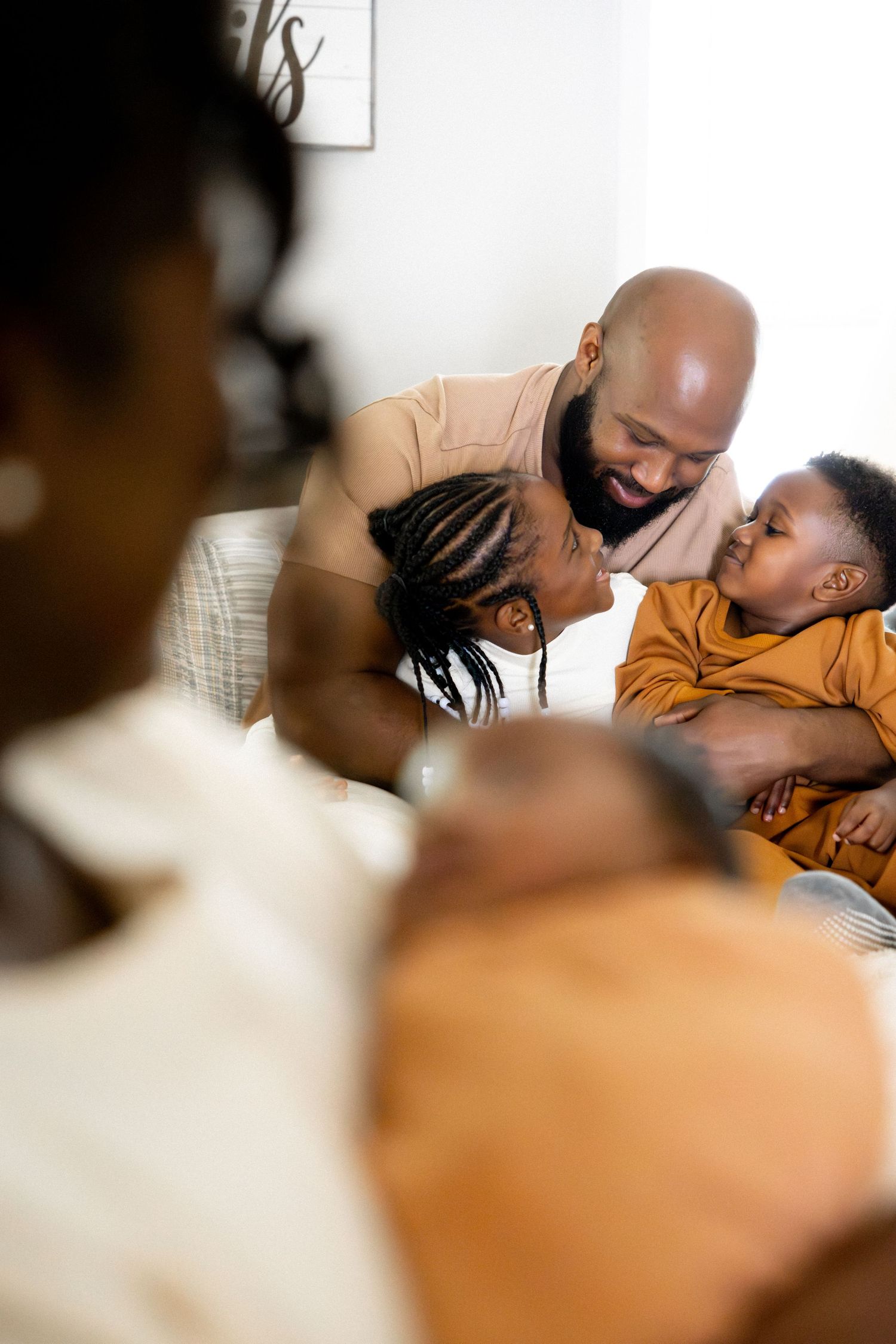Family sharing loving moments while relaxing together on white bedding.