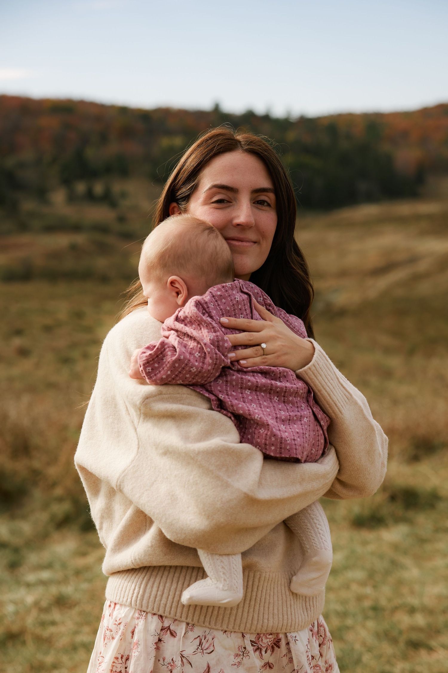 Tender outdoor family moment captured in warm autumn sunlight.