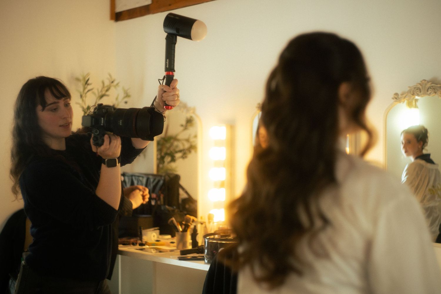 Warm-toned behind-the-scenes photo of photographers at work with lighting equipment.