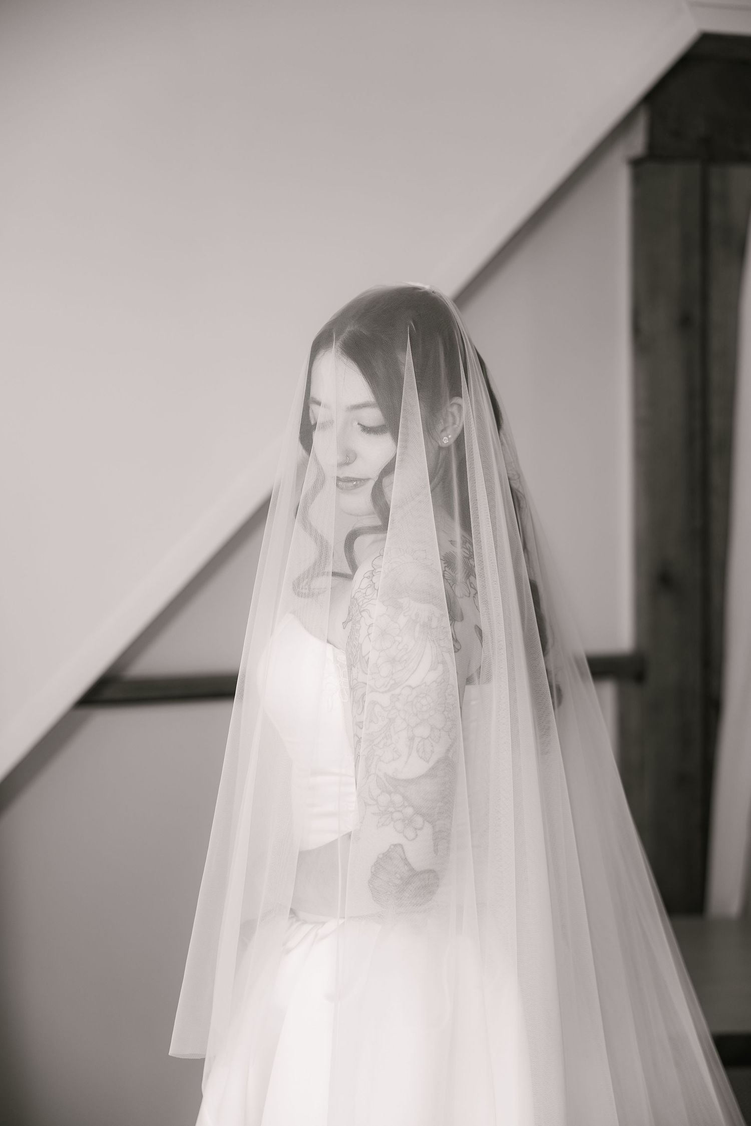 Ethereal bridal portrait through sheer white veil in black and white.