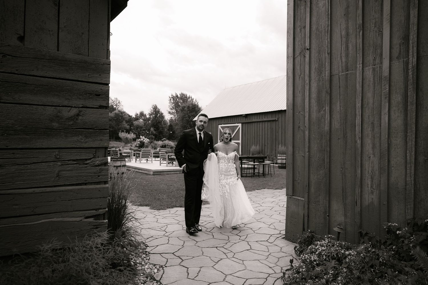 Artistic black and white wedding photos taken against rustic wooden barn walls.